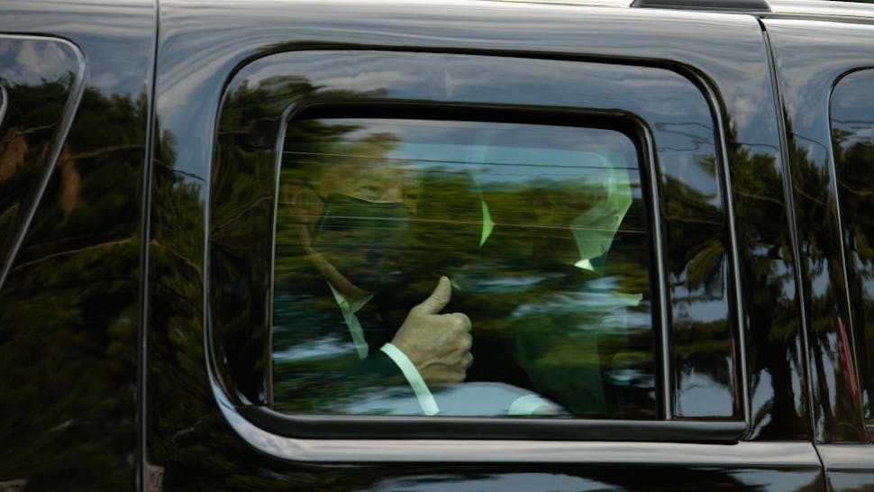 U.S. President Donald Trump wears a protective mask while giving a thumbs up as he is driven in a motorcade past supporters outside of Walter Reed National Military Medical Center in Bethesda, Maryland, U.S., on Sunday, Oct. 4, 2020. Trump briefly left his hospital in a car to greet supporters gathered outside, after posting a video on Twitter saying he was about to make a surprise visit. Photographer: