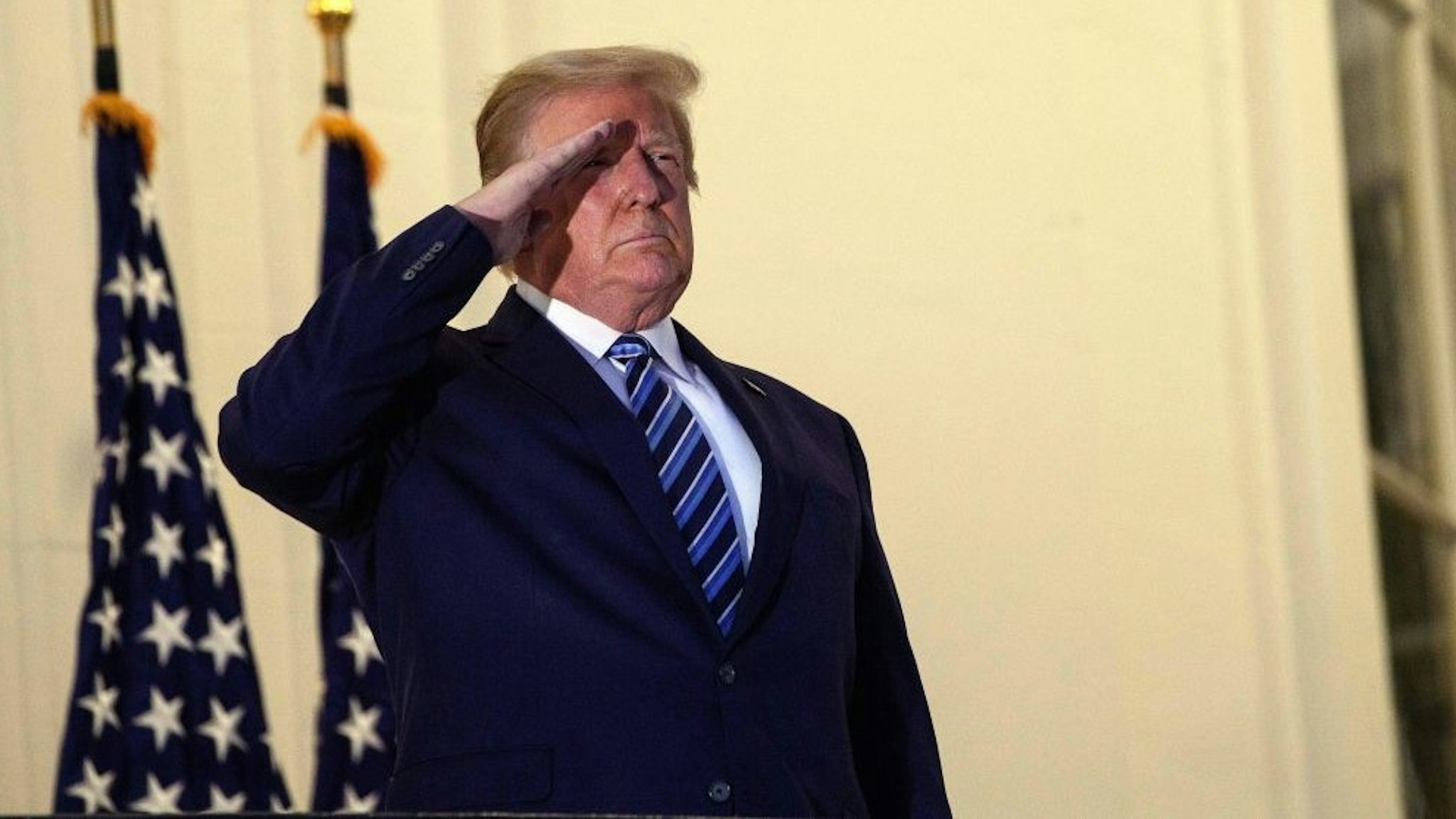 TOPSHOT - US President Donald Trump salutes from the Truman Balcony upon his return to the White House from Walter Reed Medical Center, where he underwent treatment for Covid-19, in Washington, DC, on October 5, 2020. (Photo by NICHOLAS KAMM / AFP) (Photo by