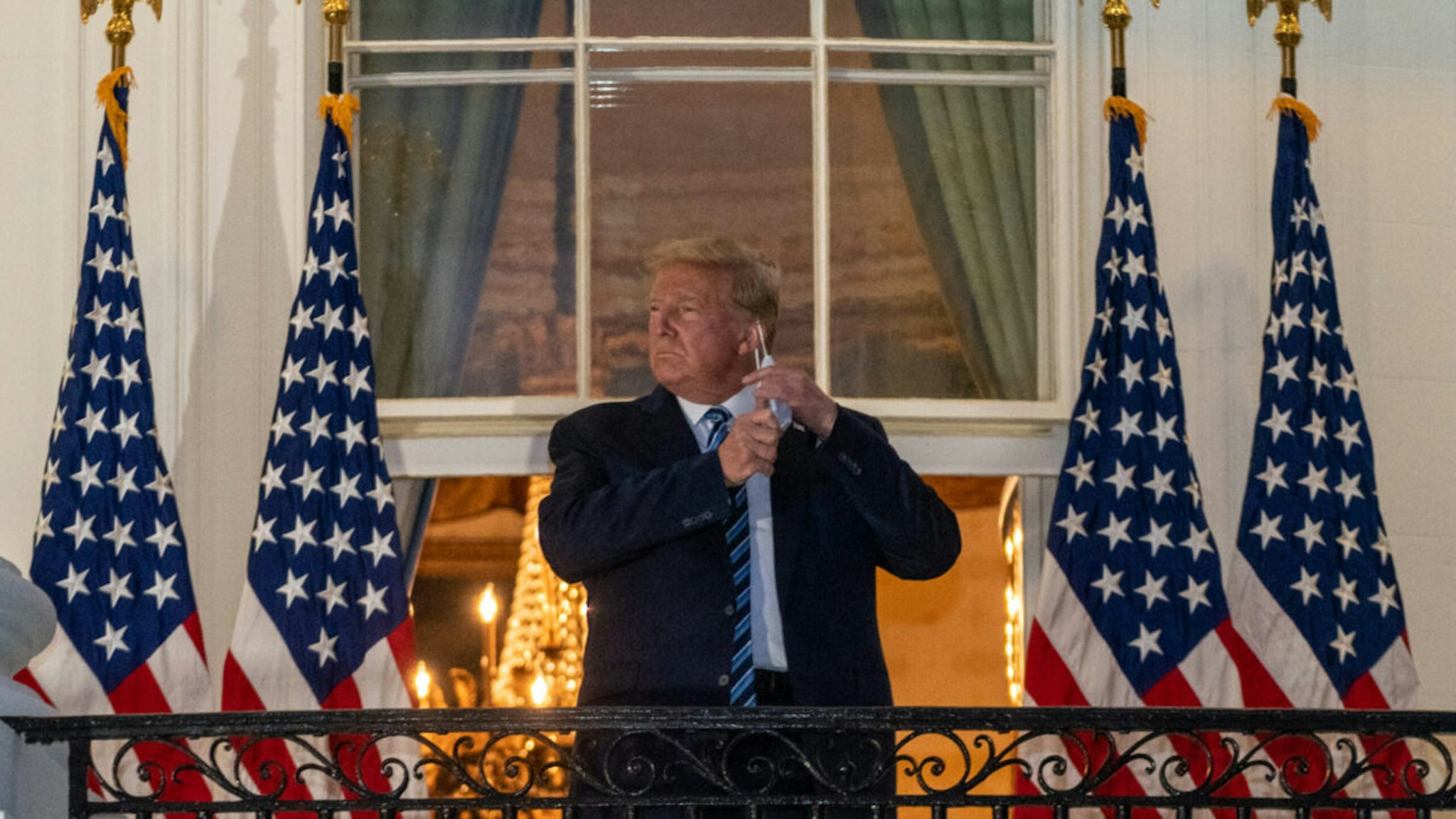U.S. President Donald Trump removes his protective mask while on the Truman Balcony of the White House after being discharged from the Walter Reed National Military Medical Center with Covid-19 in Washington, D.C., U.S., on Monday, Oct. 5, 2020.