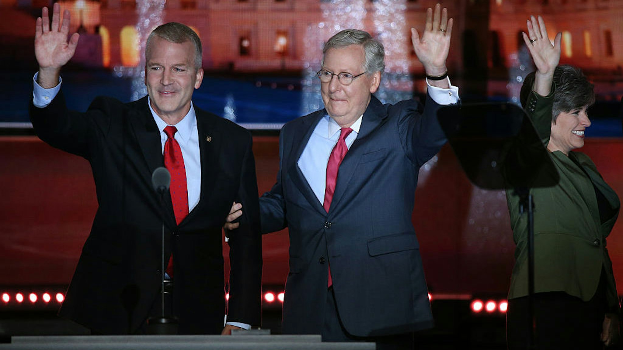 Senator Dan Sullivan, a Republican from Alaska, from left, waves on stage with Senate Majority Leader Mitch McConnell, a Republican from Kentucky, and Senator Joni Ernst, a Republican from Iowa, during the Republican National Convention (RNC) in Cleveland, Ohio, U.S., on Tuesday, July 19, 2016. Donald Trump sought to use a speech by his wife to move beyond delegate discontent at the Republican National Convention, only to have the second day open with an onslaught of accusations that his wife's speech lifted phrases from one delivered by Michelle Obama in 2008. Photographer: John Taggart/Bloomberg