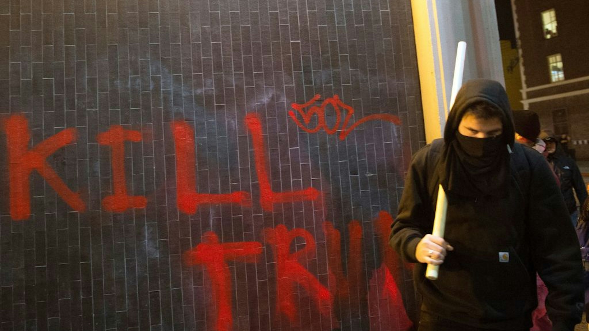 A protester walks with a pipe near graffiti in Berkeley, California on February 1, 2017. - Violent protests erupted on February 1 at the University of California at Berkeley over the scheduled appearance of a controversial editor of the conservative news website Breitbart. (Photo by Josh Edelson / AFP) (Photo by JOSH EDELSON/AFP via Getty Images)