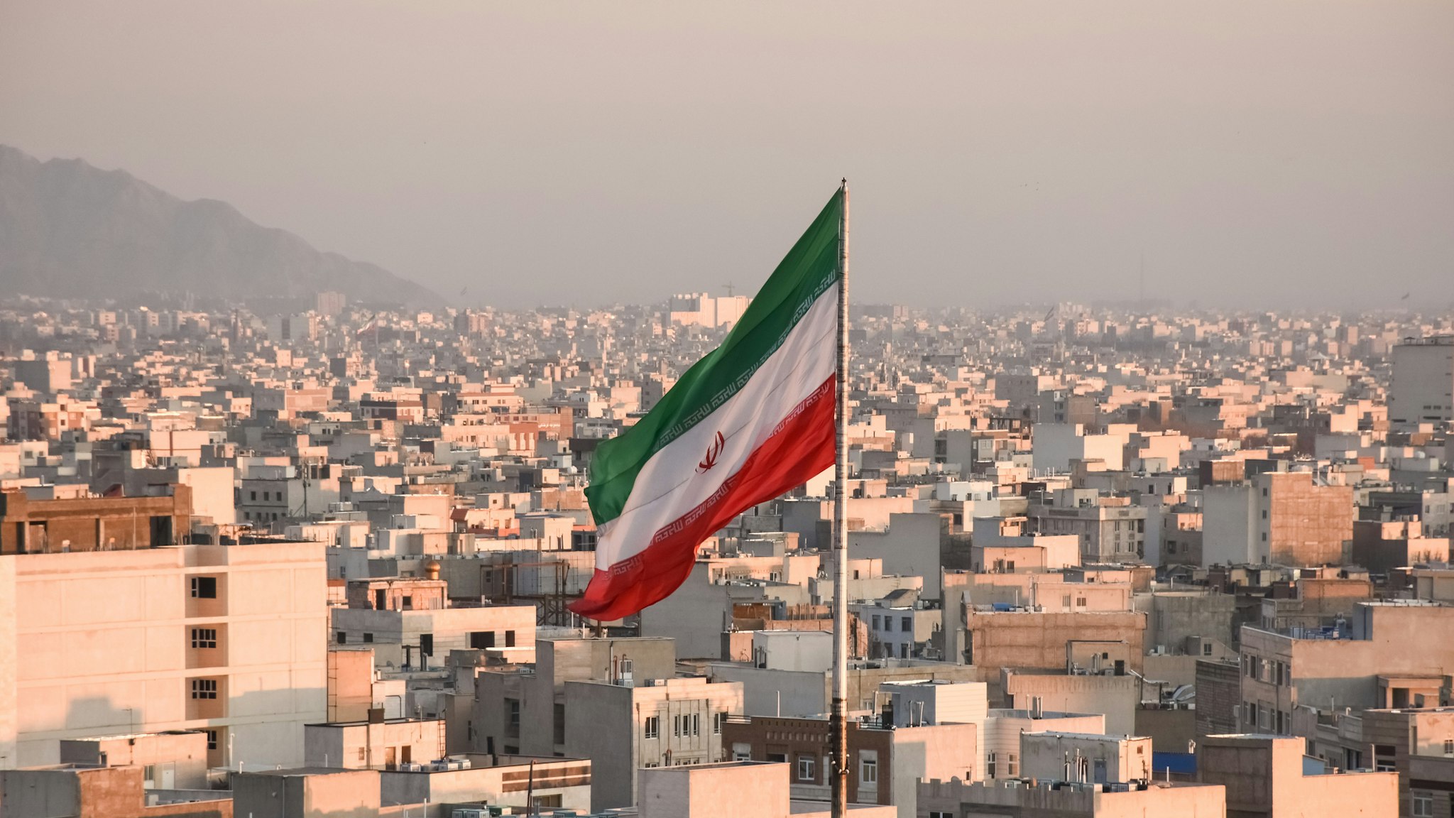Iranian flag waving with city skyline on background in Tehran, Iran - stock photo