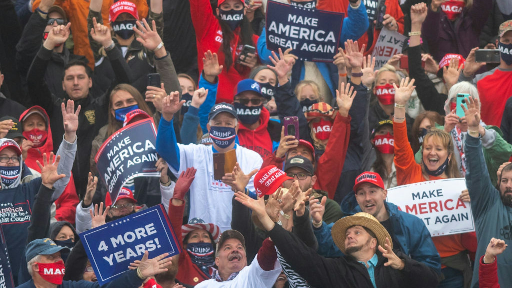 Supporters strain to catch a Make America Great Again hat thrown by President Donald Trump during a rally on October 26, 2020 in Lititz, Pennsylvania.
