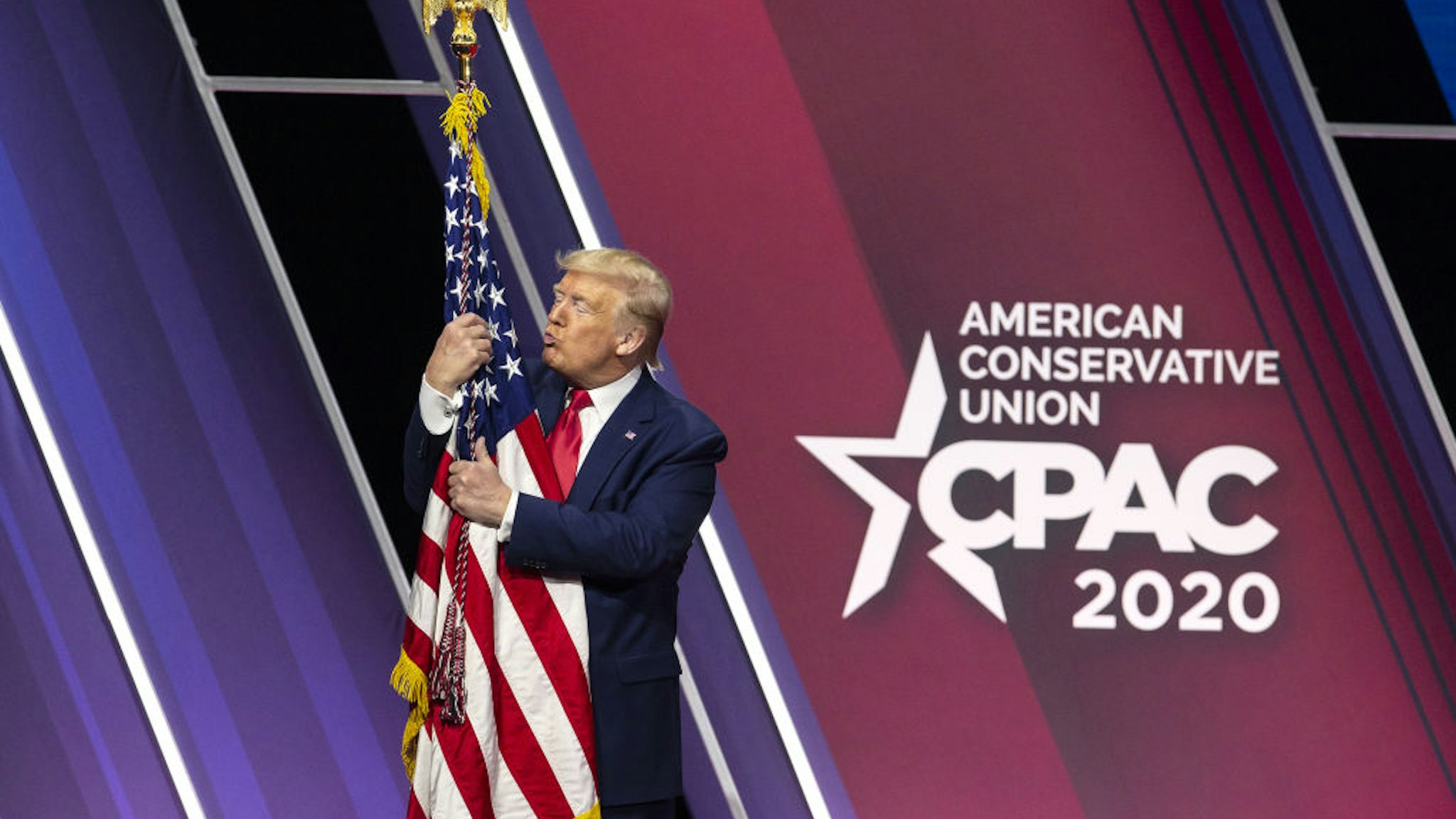 U.S. President Donald Trump hugs and kisses the American flag during the Conservative Political Action Conference (CPAC) in National Harbor, Maryland, U.S., on Saturday, Feb. 29, 2020.