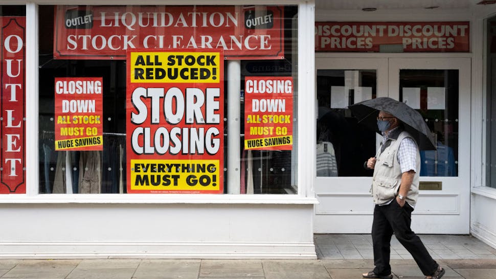Business closures A man wearing a face mask walks past a shop with signs in the window saying its closing down in Newport town centre on October 31, 2020 in Newport, Wales.