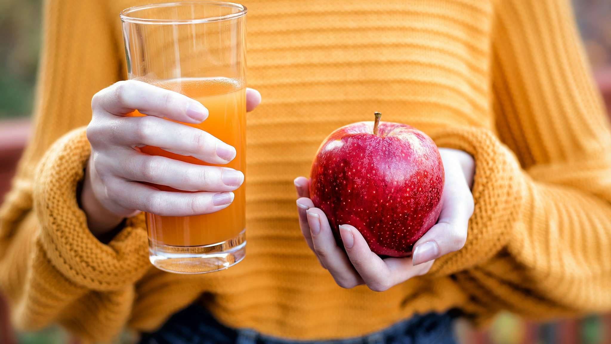 Young woman holding glass of apple juice and fresh apple - stock photo