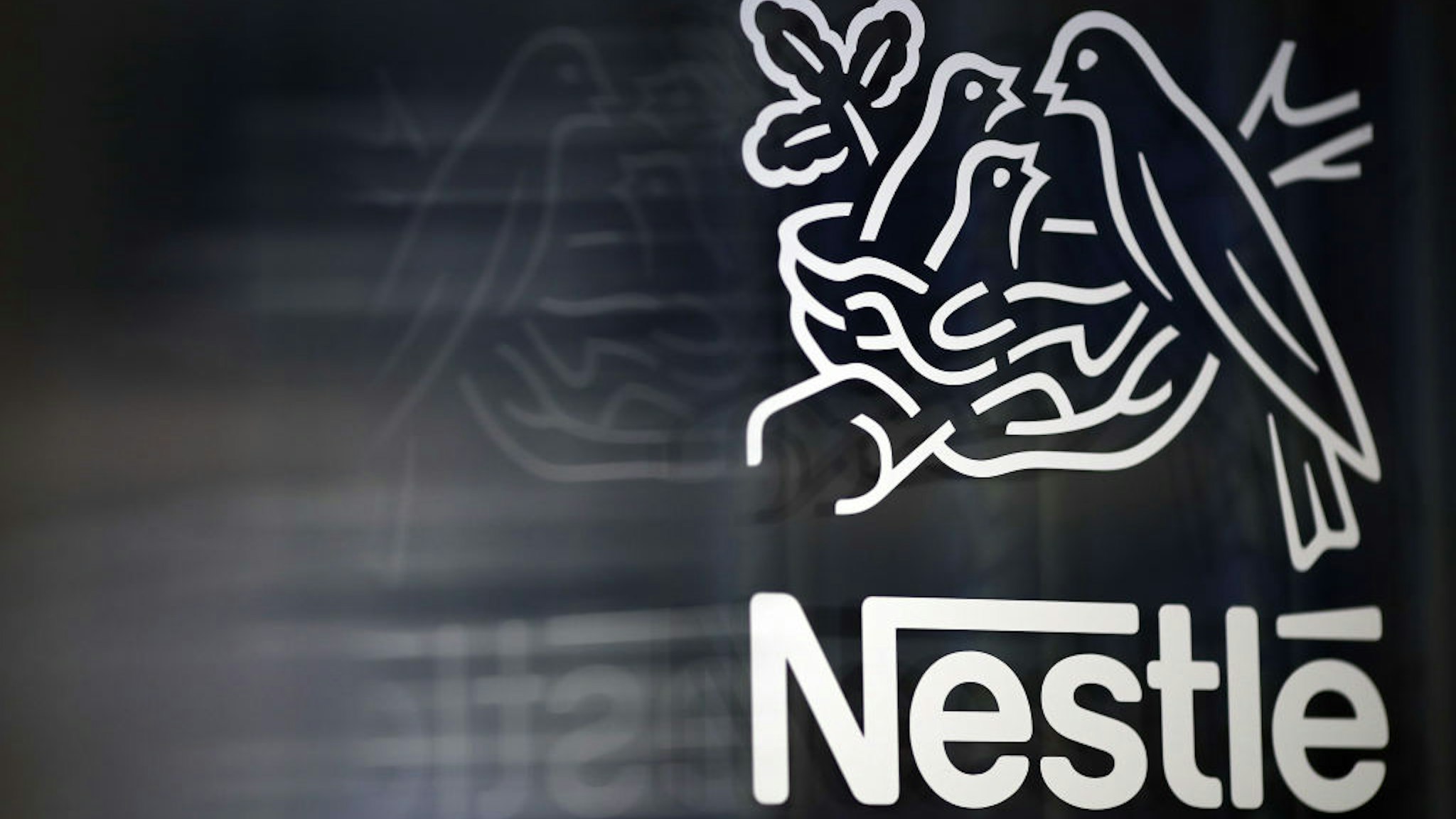 A Nestle birds nest logo is displayed on a glass door ahead of a news conference announcing the company's full year results in Vevey, Switzerland, on Thursday, Feb. 15, 2018.
