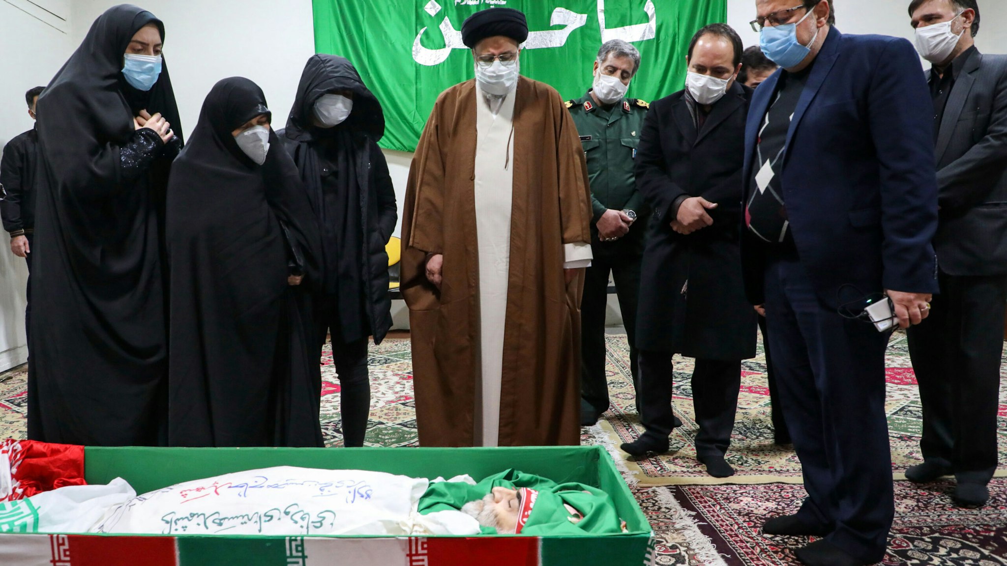 Iran's Judiciary Chief Ayatollah Ebrahim Raisi (C) pays respects to the body of slain scientist Mohsen Fakhrizadeh among his family, in the capital Tehran on November 28, 2020. - Mohsen Fakhrizadeh, dubbed by Israel as the "father" of Iran's nuclear programme, died on November 27 after being seriously wounded when assailants targeted his car and engaged in a gunfight with his bodyguards outside Tehran, according to Iran's defence ministry. The assassination comes less than two months before US President-elect Joe Biden is due to take office, after a tumultuous four years of hawkish foreign policy in the Middle East under President Donald Trump.