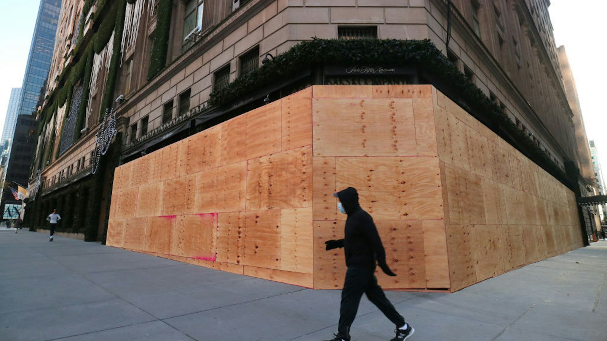 NEW YORK, NY - OCTOBER 31: A person walks past a boarded up entrance and windows of the Saks Fifth Avenue store on Fifth Avenue ahead of expected election day protests on October 31, 2020 in New York City. (Photo by Gary Hershorn/Getty Images)