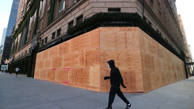 NEW YORK, NY - OCTOBER 31: A person walks past a boarded up entrance and windows of the Saks Fifth Avenue store on Fifth Avenue ahead of expected election day protests on October 31, 2020 in New York City. (Photo by Gary Hershorn/Getty Images)