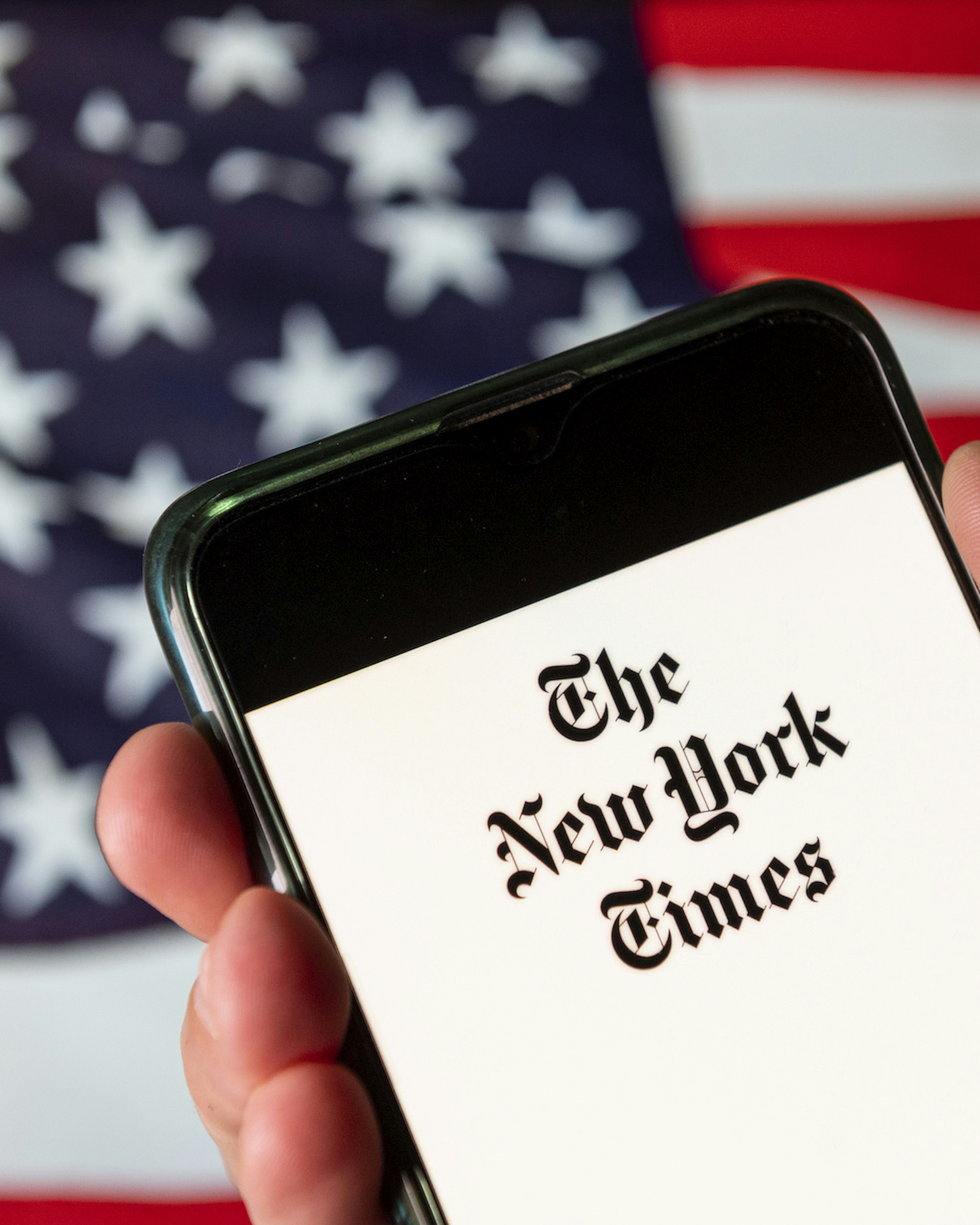 In this photo illustration the American newspaper The New York Times (NYT) logo is seen on an Android mobile device with United States of America flag in the background. (Photo Illustration by Budrul Chukrut/SOPA Images/LightRocket via Getty Images)