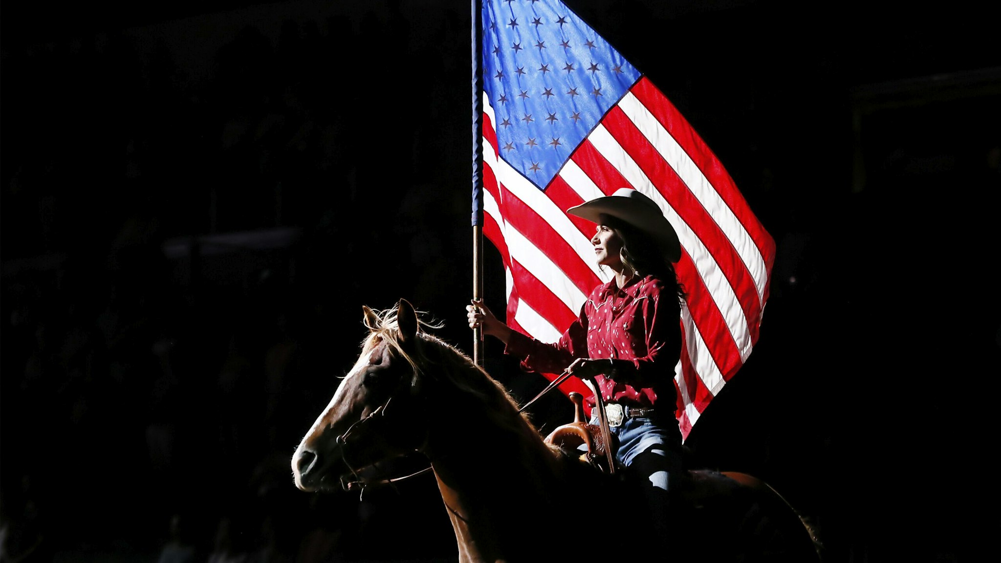 SIOUX FALLS, SD - JULY 11: South Dakota's Governor Kristi Noem holds the U.S flag riding a horse during the Monster Energy Team Challenge, on July 11, 2020, at the Denny Sanford PREMIER Center, Sioux Falls, SD.