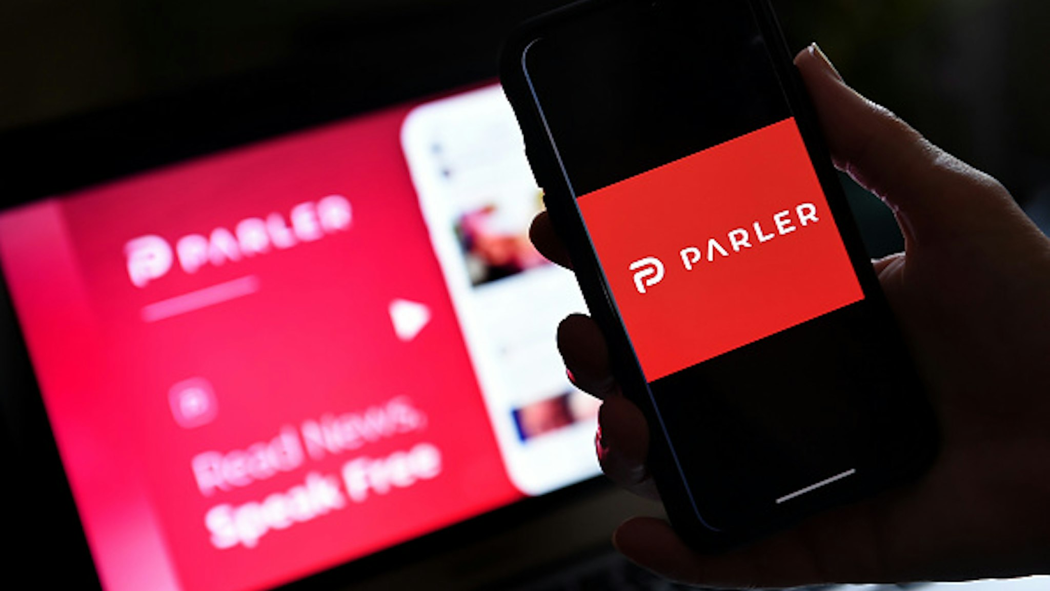 This illustration picture shows social media application logo from Parler displayed on a smartphone with its website in the background in Arlington, Virginia on July 2, 2020. - Amid rising turmoil in social media, recently formed social network Parler is gaining with prominent political conservatives who claim their voices are being silenced by Silicon Valley giants. Parler, founded in Nevada in 2018, bills itself as an alternative to "ideological suppression" at other social networks.