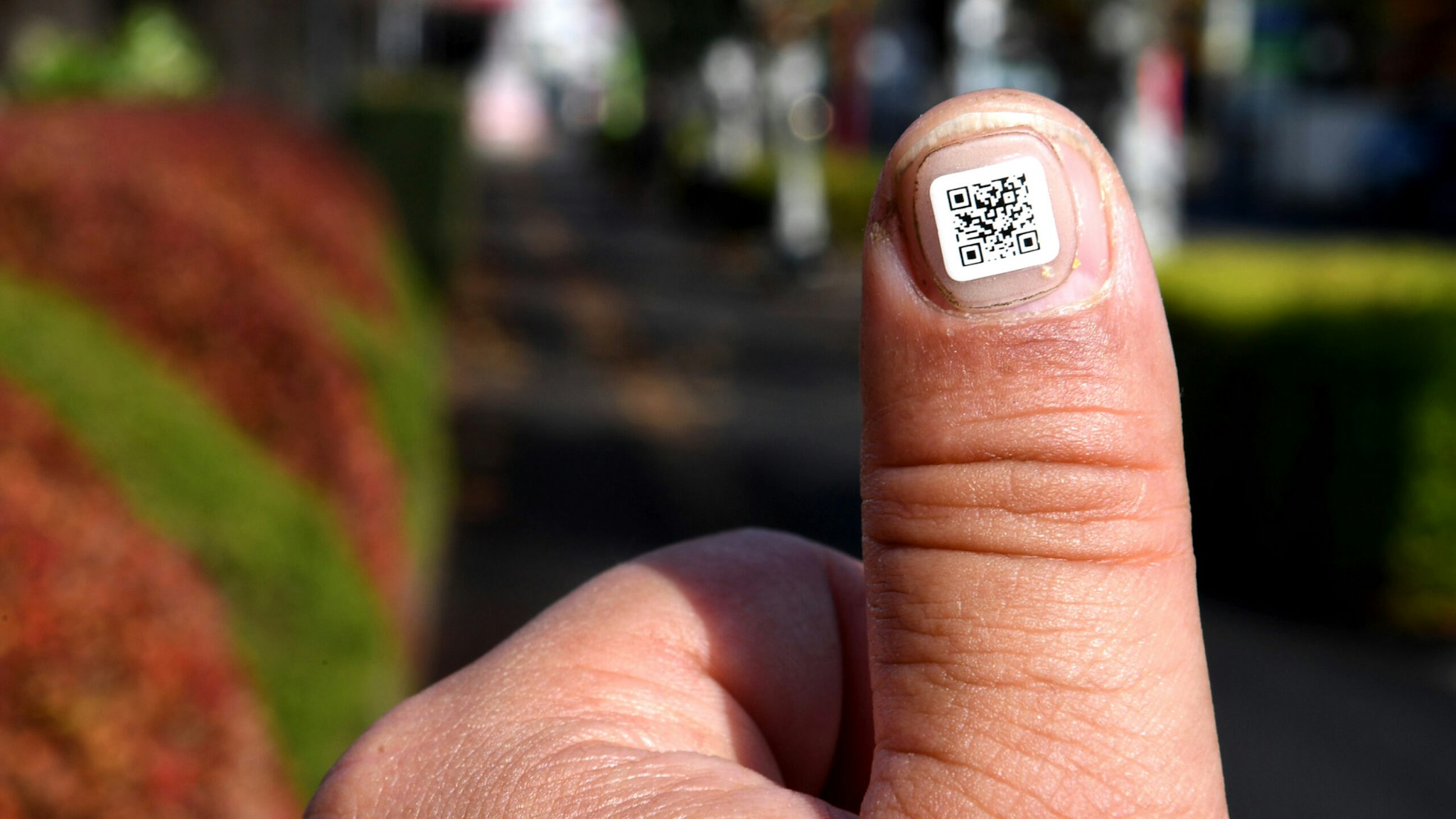 This picture taken on December 5, 2016 shows a city officer displaying a QR code on his fingernail near the Iruma city hall in Iruma, Saitama prefecture, a western suburb of Tokyo. A Japanese city has introduced a novel way to keep track of senior citizens with dementia who are prone to getting lost -- tagging their fingers and toes with scan-able barcodes. A company in Iruma, north of Tokyo, developed tiny nail stickers, each of which carries a unique identity number to help concerned families find missing loved ones, according to the city's social welfare office