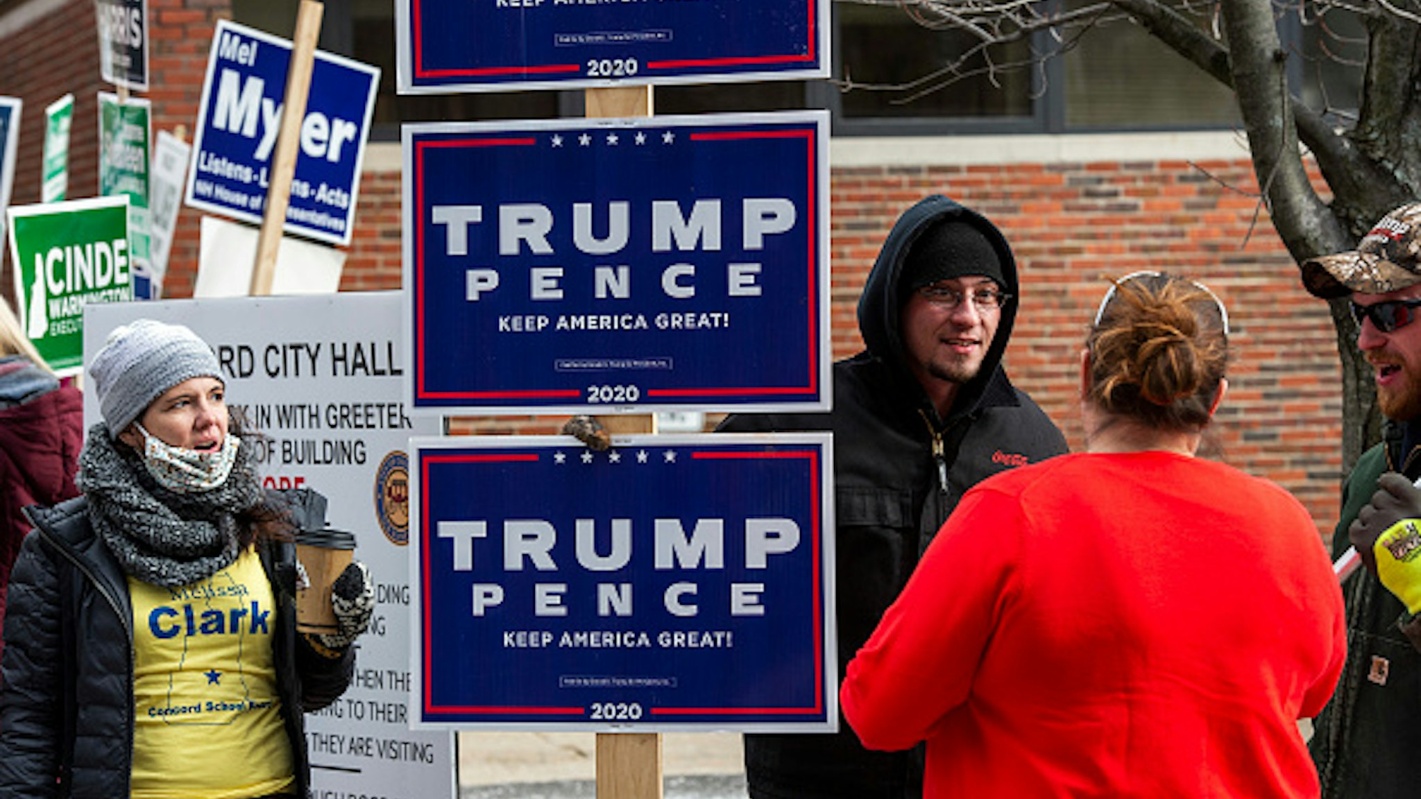 A woman brings coffee to sign holders outside a polling station on Election Day in Concord, New Hampshire on November 3, 2020. - Americans were voting on Tuesday under the shadow of a surging coronavirus pandemic to decide whether to reelect Republican Donald Trump, one of the most polarizing presidents in US history, or send Democrat Joe Biden to the White House