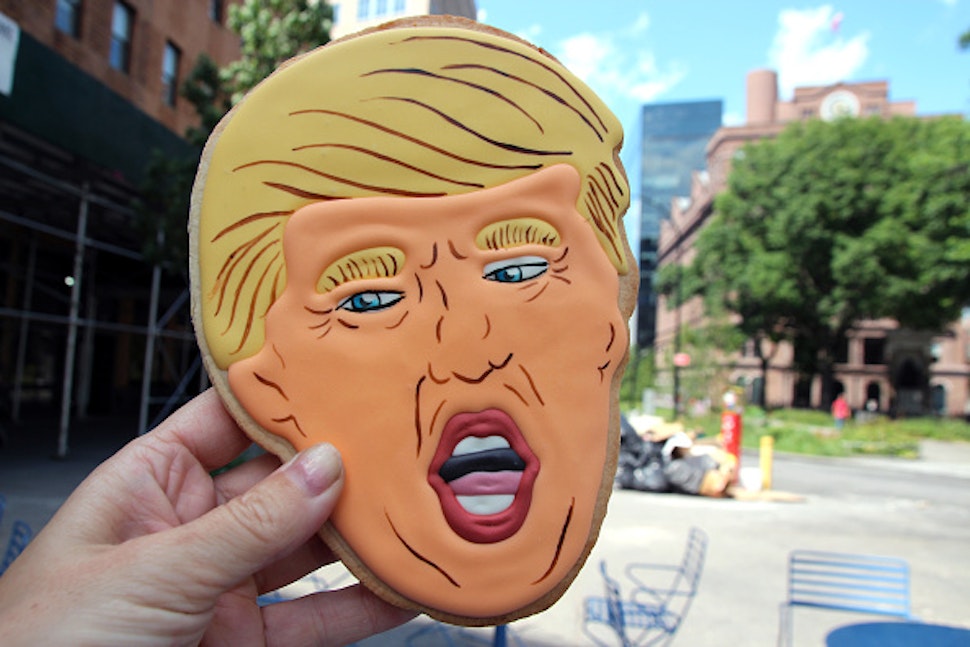 11 July 2018, USA, New York: The face of Donald Trump is painted onto a large cookie with a thick layer of orange icing, and is being held up in front of a bakery in the East Village. The cookie is not exactly cheap: it costs 16 dollars (about 14 euros).