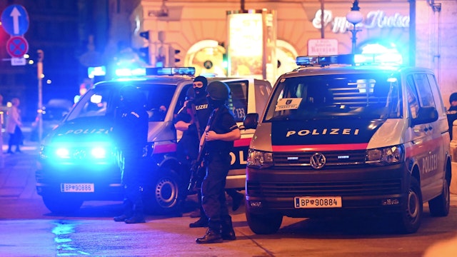 Police cars and policemen stand in the central Vienna on November 2, 2020, following a shooting near a synagogue. - Multiple gunshots were fired in central Vienna on the evening of November 2, 2020, according to police, with the location of the incident close to a major synagogue. Police urged residents to keep away from all public places or public transport. One attacker was "dead" and another "on the run", with one police officer being seriously injured, Austria's interior ministry said according to news agency APA.