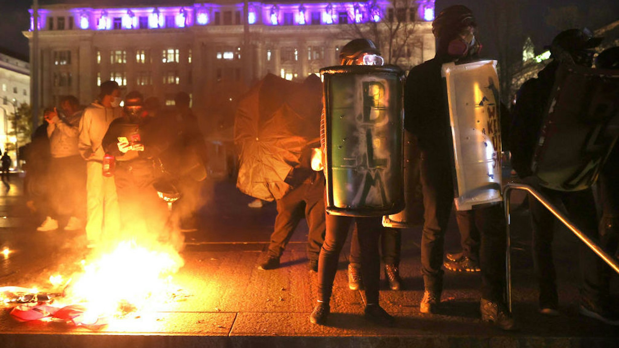 WASHINGTON, DC - NOVEMBER 14: Black Lives Matter protesters hold shields as they stand next to a small fire during a protest following the “Million MAGA March” from Freedom Plaza to the Supreme Court, on November 14, 2020 in Washington, DC. Supporters of U.S. President Donald Trump gathered to protest the outcome of the 2020 presidential election.