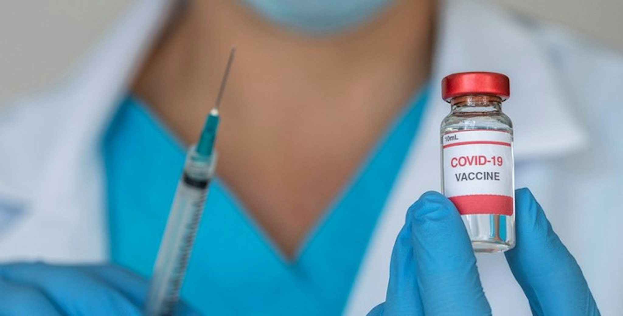 Close-up of doctors hands holding Covid-19 vaccine and syringe