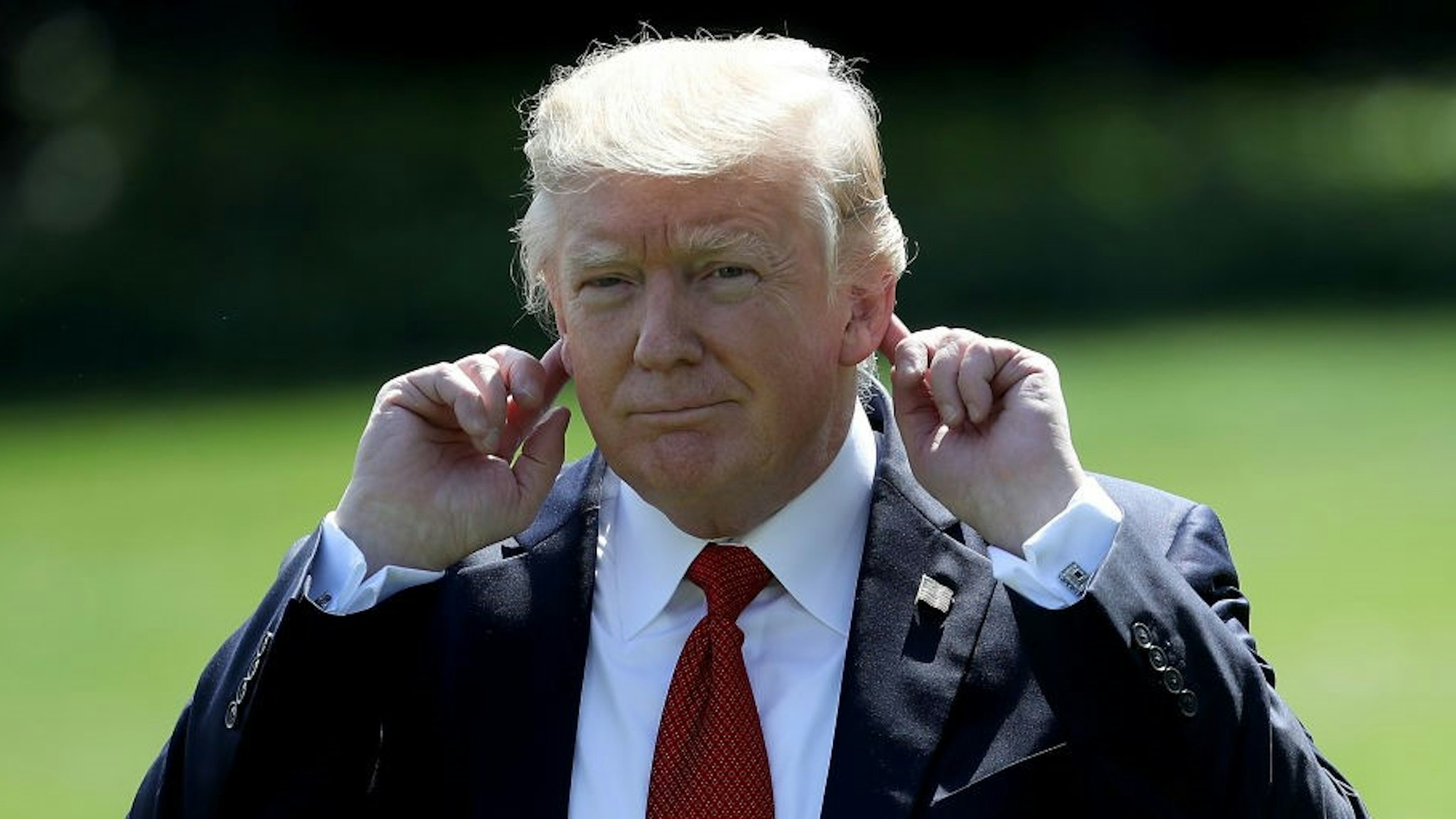 WASHINGTON, DC - SEPTEMBER 08: US President Donald Trump points to his ears as he tries to hear shouted questions from reporters while departing the White House for Camp David September 8, 2017 in Washington, DC. Trump is scheduled to meet with members of his Cabinet this weekend while at Camp David. (Photo by