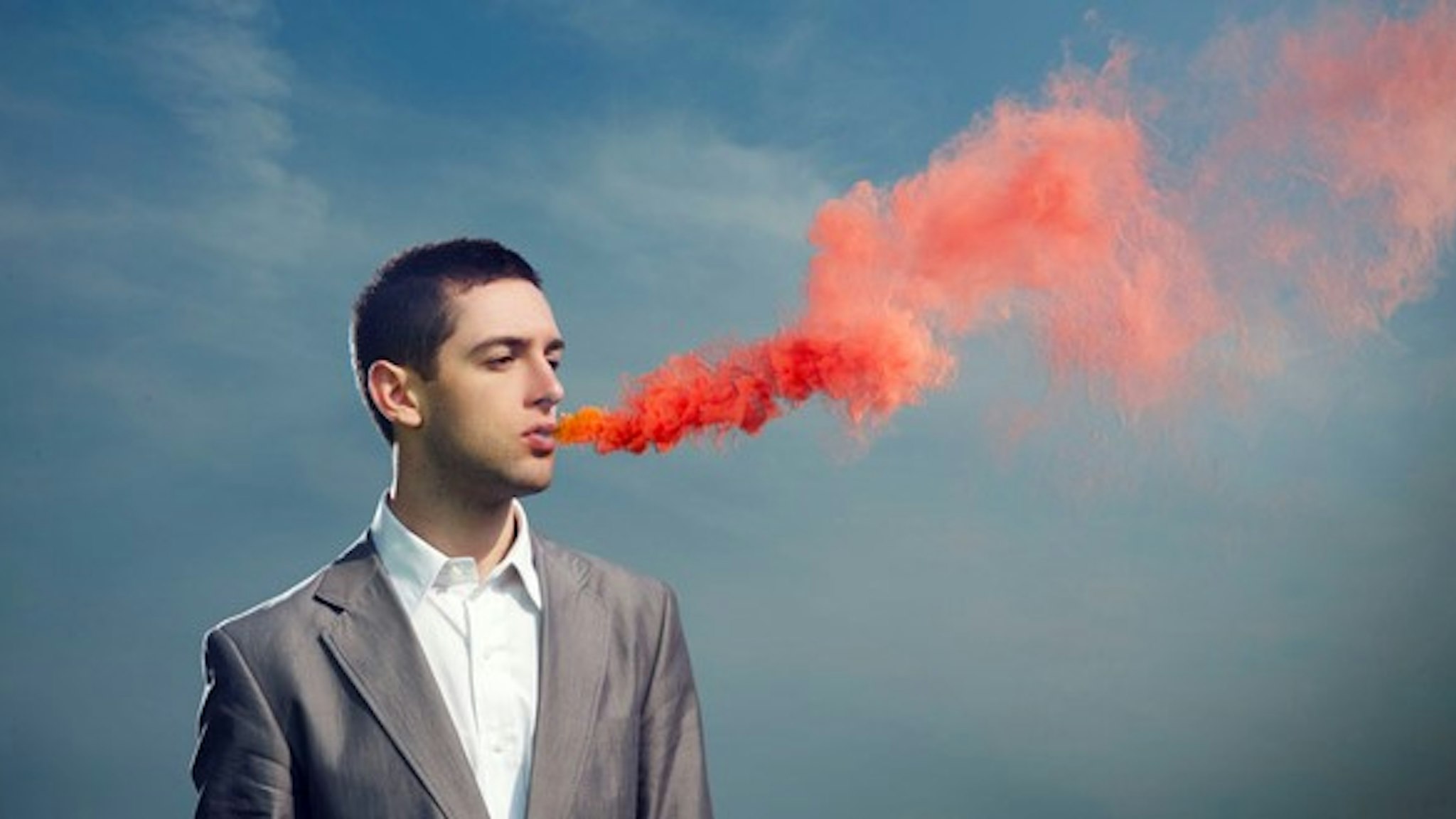 man breathing red smoke