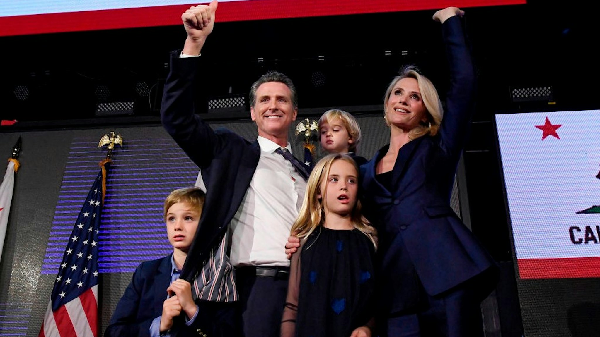 LOS ANGELES, CA - NOVEMBER 06: Democratic gubernatorial candidate Gavin Newsom holding his son Dutch, 2, and standing with his son Hunter, 7, wife Jennifer Siebel Newsom and daughter Montana, 9, as he waves to supporters during election night event on November 6, 2018 in Los Angeles, California. Newsom defeated Republican Gubernatorial candidate John Cox. (Photo by
