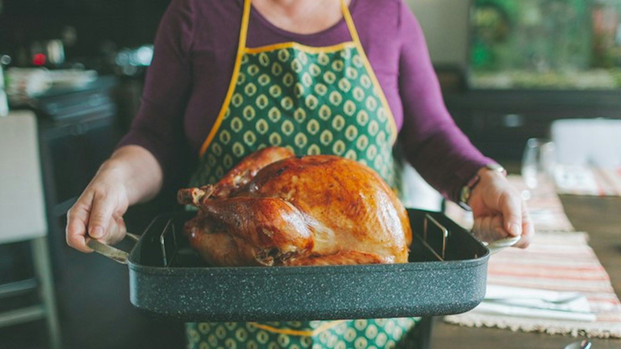 Midsection Of Woman Carrying Tray With Roast Turkey In Kitchen