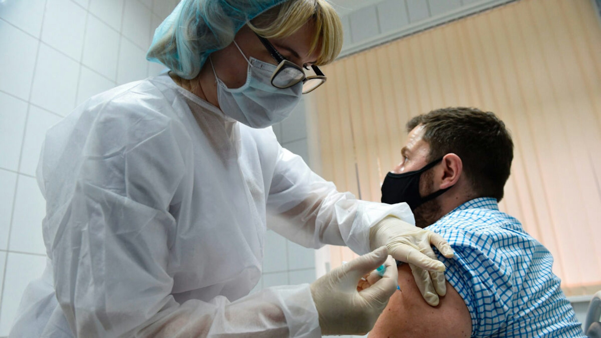 A nurse inoculates volunteer Ilya Dubrovin, 36, with Russia's new coronavirus vaccine in a post-registration trials at a clinic in Moscow on September 10, 2020.