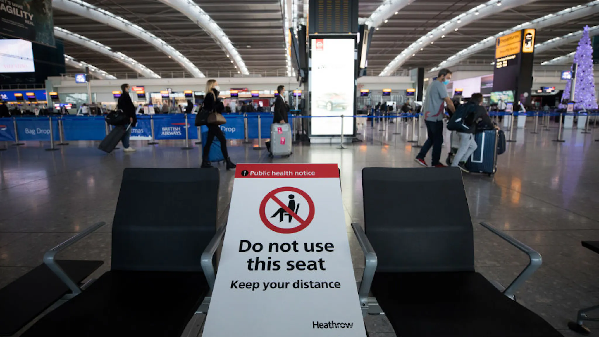 Festive Season Travel At London Airports A social distancing sign on a seat in the check-in area in at London Heathrow Airport Ltd. in London, U.K., on Saturday, Dec. 19, 2020. The pandemic has put a third of all tourism jobs at risk, and airlines around the world have said they need as much as $200 billion in bailouts.