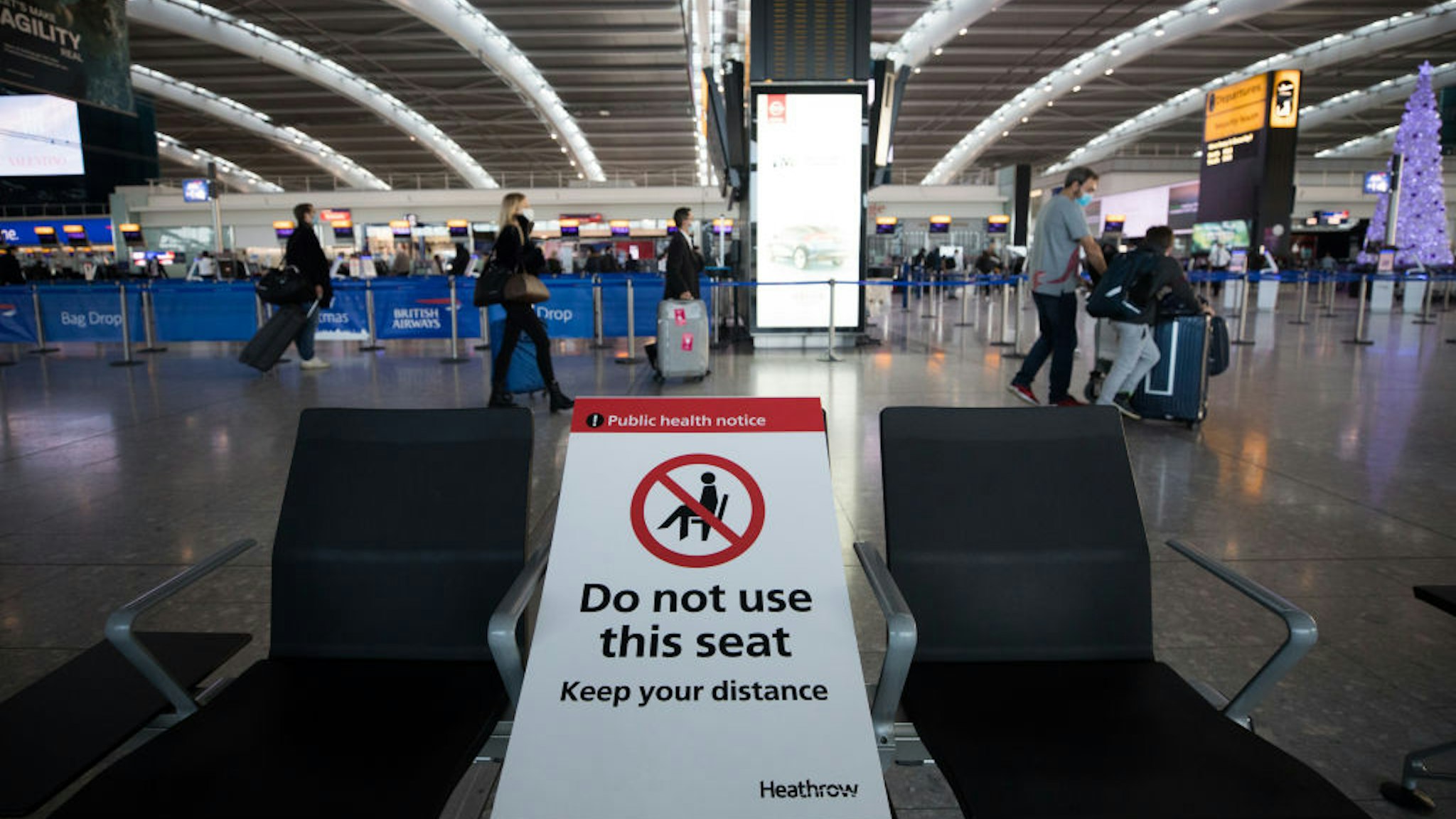 A social distancing sign on a seat in the check-in area in at London Heathrow Airport Ltd. in London, U.K., on Saturday, Dec. 19, 2020. The pandemic has put a third of all tourism jobs at risk, and airlines around the world have said they need as much as $200 billion in bailouts.