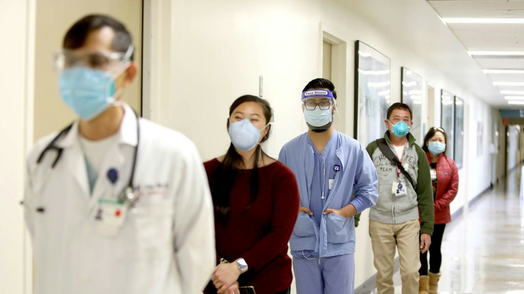 DALY CITY, CA - DEC. 21: Donning a mask and face shield, Roman Romo, center, waits in line with other staff members to receive a coronavirus vaccine at Seton Medical Center on Monday, December 21, 2020, in Daly City, California.