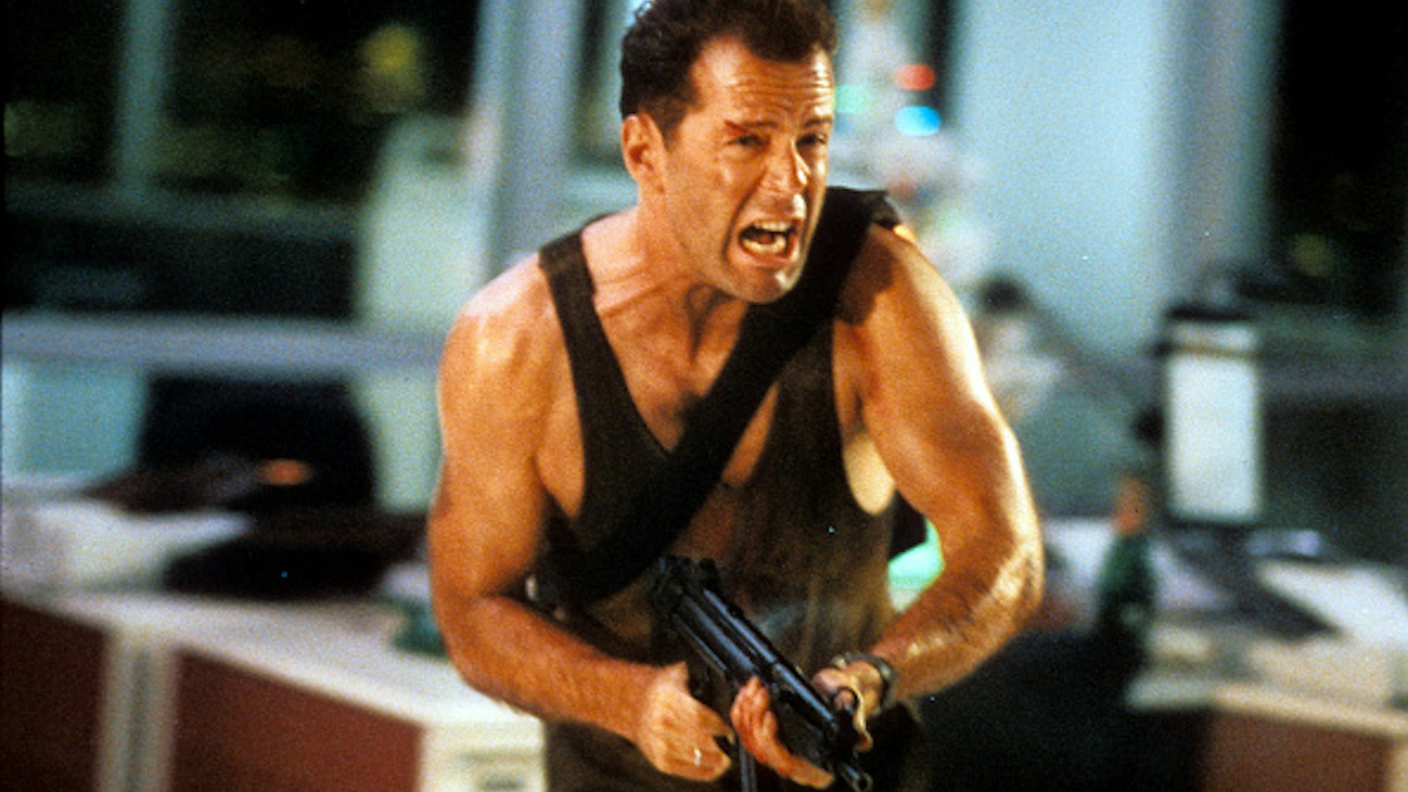 Bruce Willis running with automatic weapon in a scene from the film 'Die Hard', 1988.