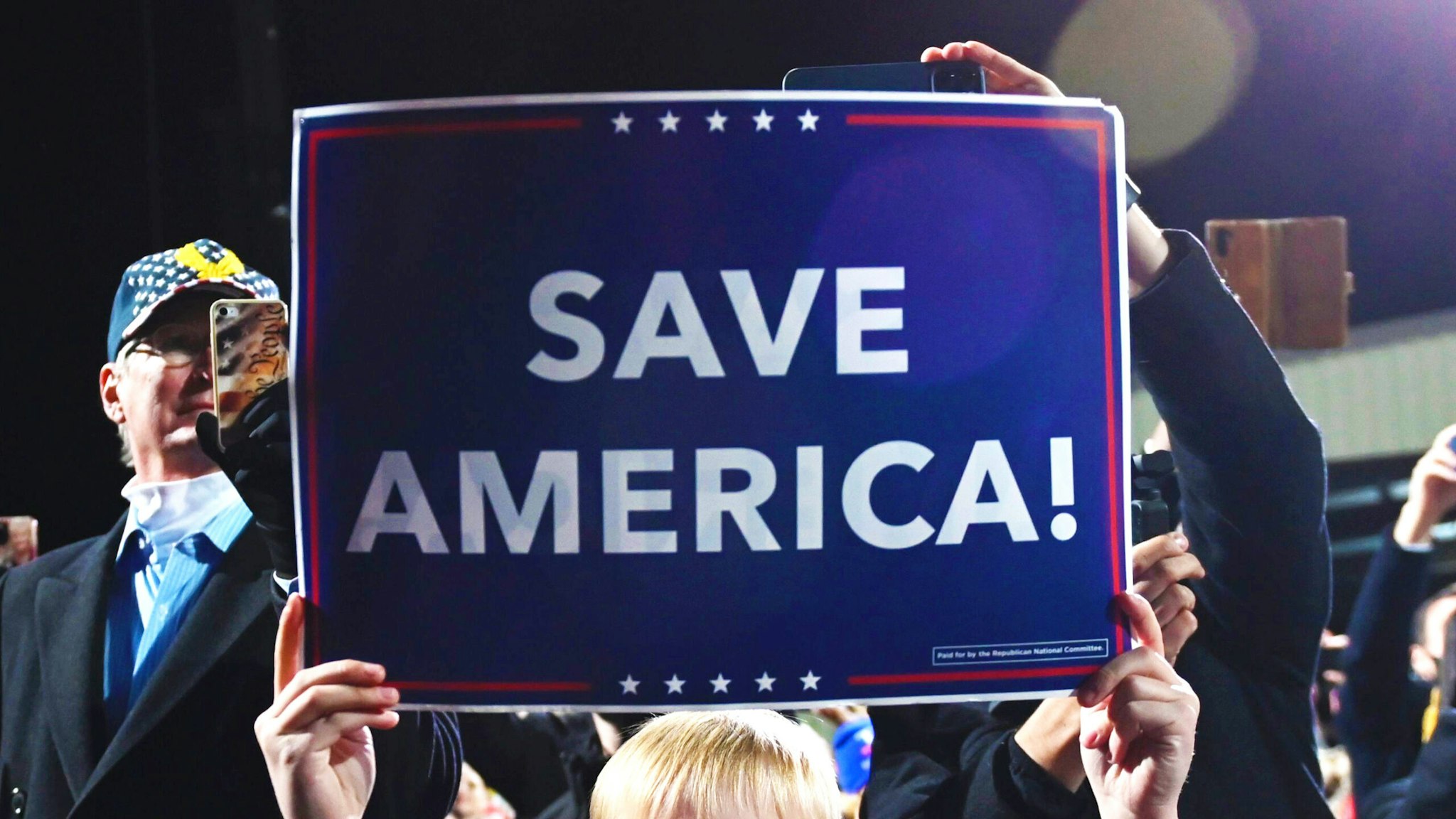 A boy holds a "Save America" sign as US president Donald Trump speaks at a rally to support Republican Senate candidates at Valdosta Regional Airport in Valdosta, Georgia on December 5, 2020. - President Donald Trump ventures out of Washington on Saturday for his first political appearance since his election defeat to Joe Biden, campaigning in Georgia where two run-off races will decide the fate of the US Senate.