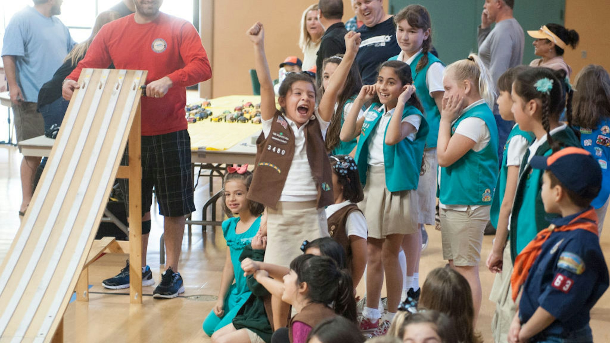 Starter Elyas Balta, at left, smiles as a Girl Scout celebrates an early victory at the combined Cub Scout/Girl Scout Pinewood Derby races at St. Norbert Catholic School in Orange Saturday.