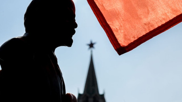 TOPSHOT - A red flag is seen above a bust of the Soviet state founder and revolutionary leader Vladimir Ilyich Ulyanov aka Lenin as Russian Communist party members and supporters attend a flower-laying ceremony marking the 149th anniversary of his birth, on Red Square in Moscow, April 22, 2019.