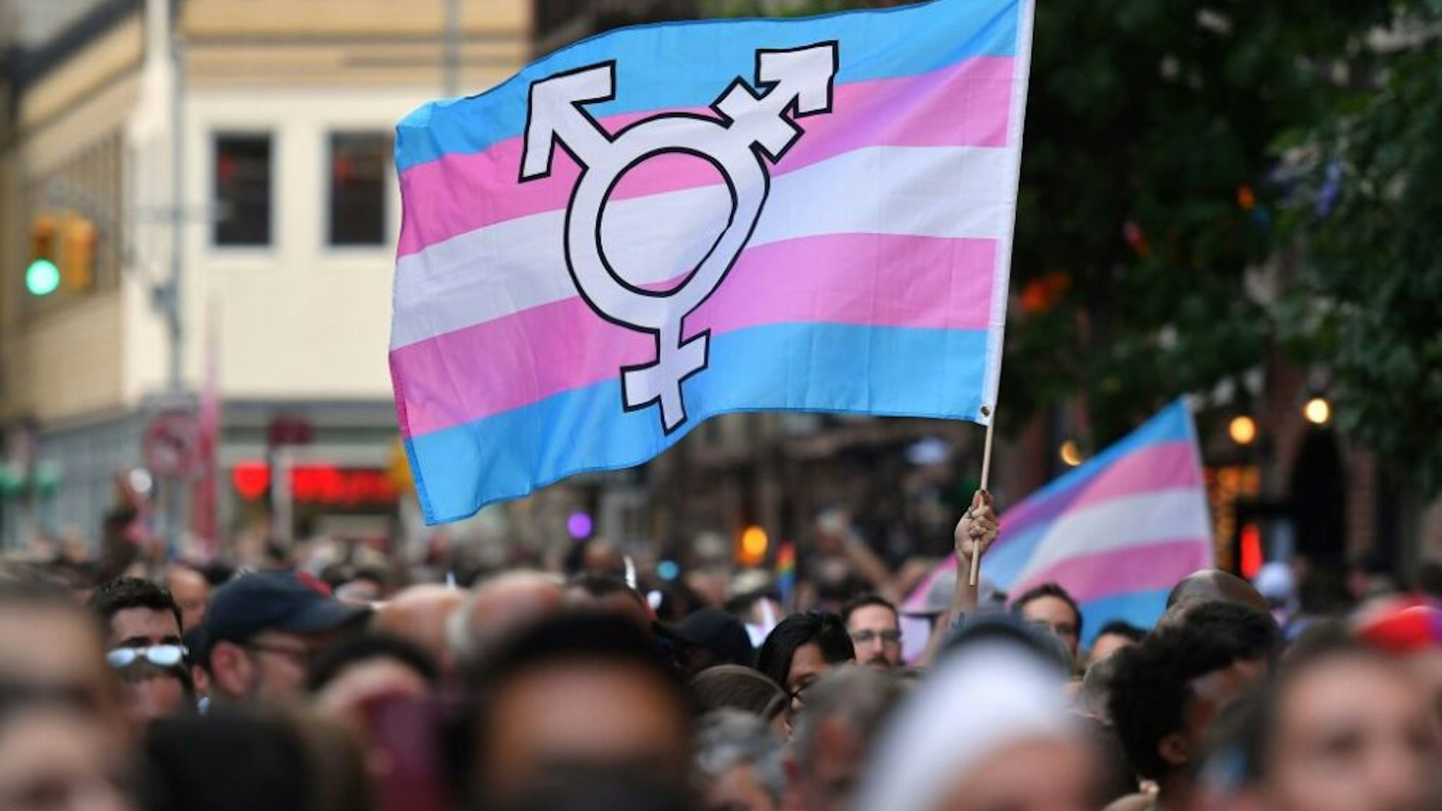 A person holds a transgender pride flag as people gather on Christopher Street outside the Stonewall Inn for a rally to mark the 50th anniversary of the Stonewall Riots in New York, June 28, 2019. - The June 1969 riots, sparked by repeated police raids on the Stonewall Inn -- a well-known gay bar in New York's Greenwich Village -- proved to be a turning point in the LGBTQ community's struggle for civil rights.