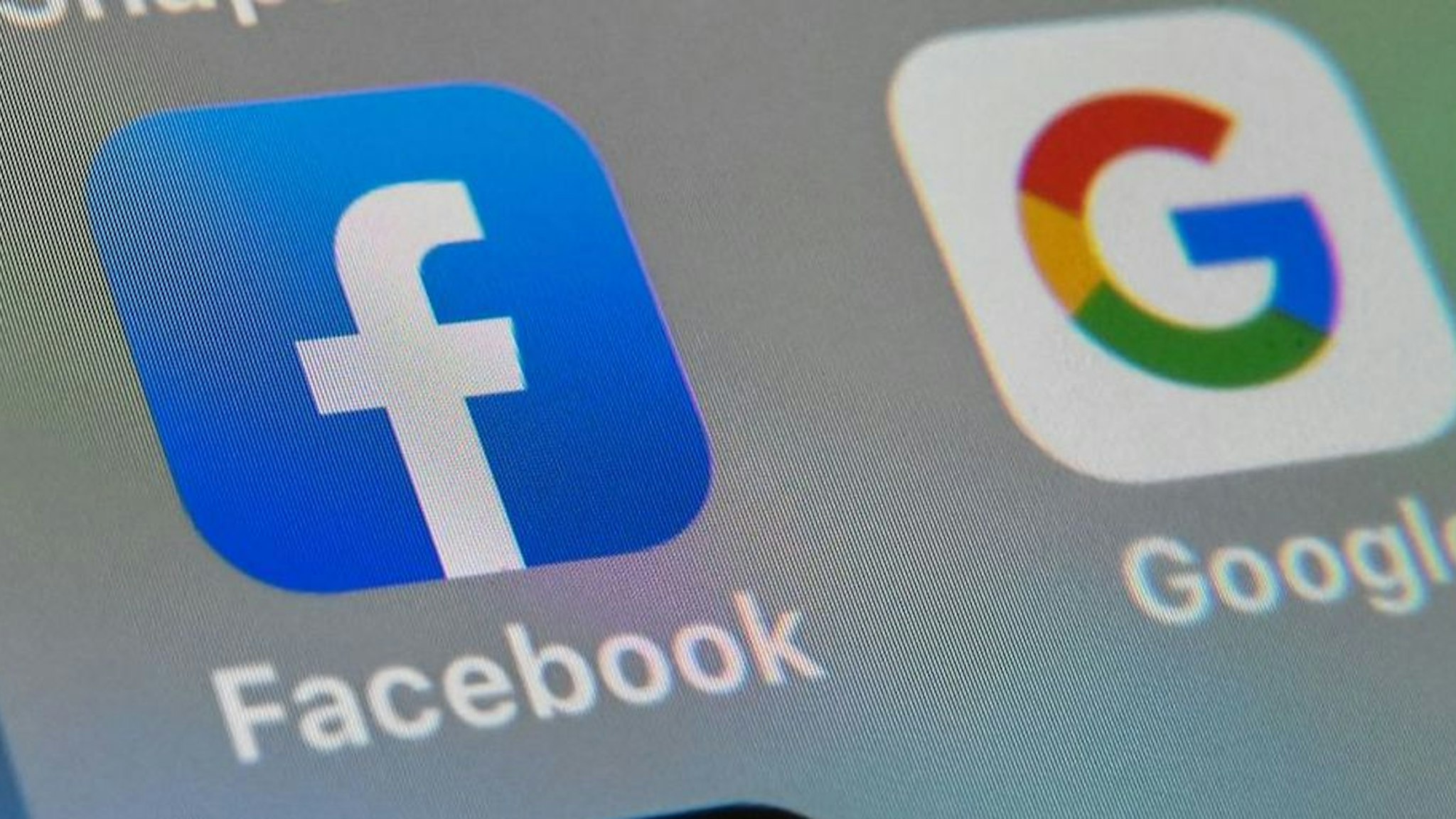 This file photo taken on October 1, 2019, shows the logos of mobile apps Facebook and Google displayed on a tablet in Lille, France