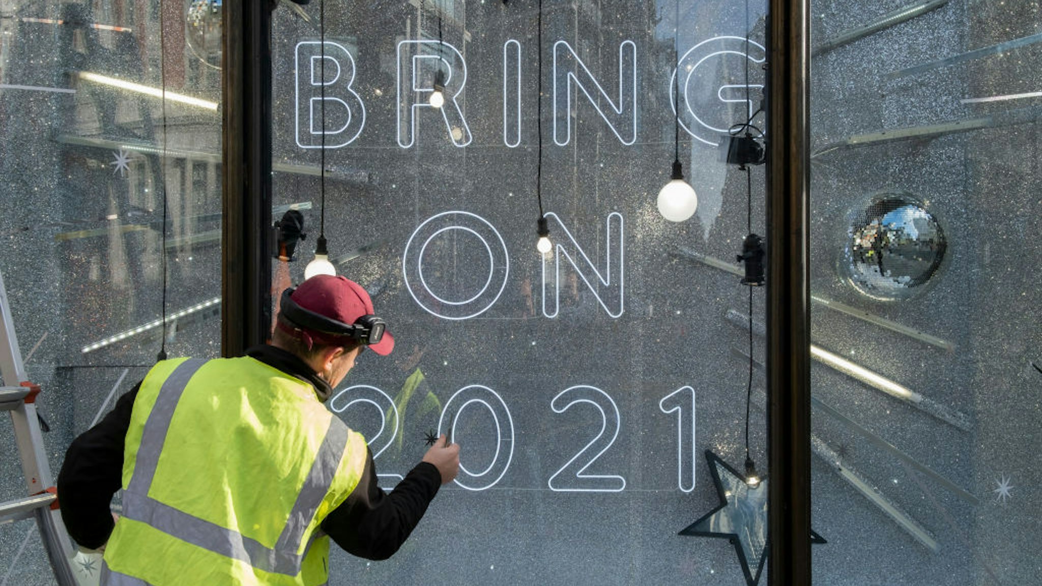 After a bleak year of Coronavirus pandemic misery, a contractor applies stars to window glass in Harvey Nichols's Christmas-themed window which urges Londoners to be optimistic for the coming year, on 13th November 2020, in London, England. (Photo by Richard Baker / In Pictures via Getty Images)