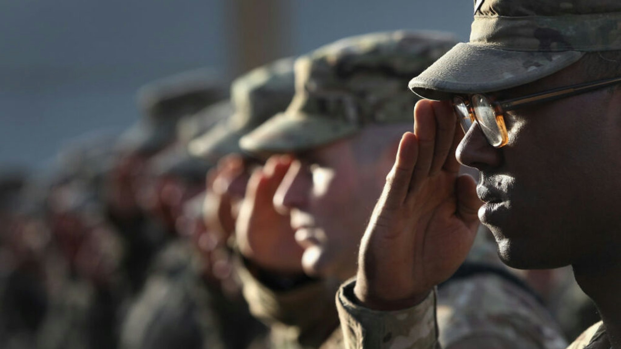 BAGRAM, AFGHANISTAN - SEPTEMBER 11: U.S. Army soldiers salute during the national anthem during the an anniversary ceremony of the terrorist attacks on September 11, 2001 on September 11, 2011 at Bagram Air Field, Afghanistan. Ten years after the 9/11 attacks in the United States and after almost a decade war in Afghanistan, American soldiers paid their respects in a solemn observence of the tragic day.