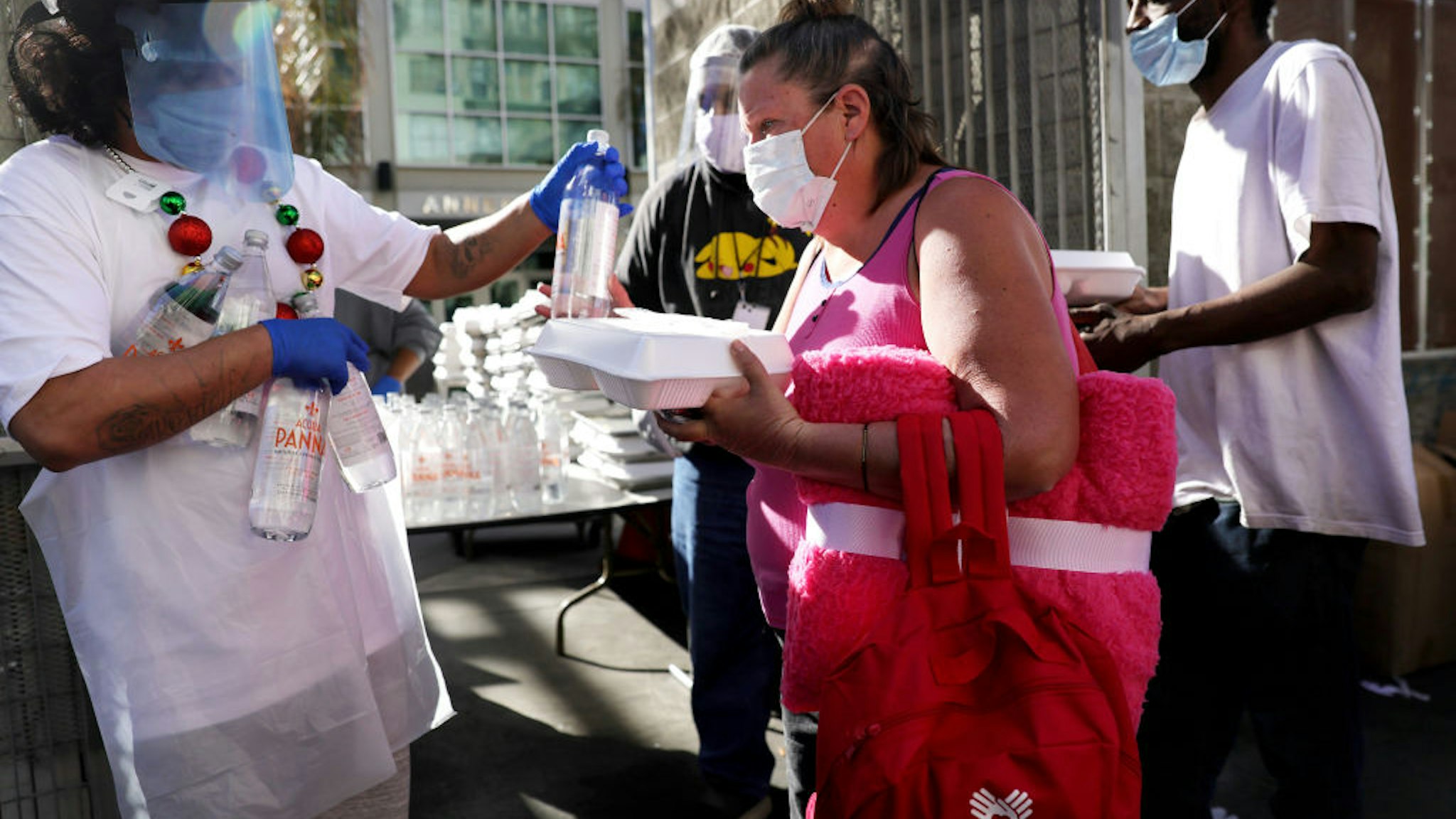 People receive a holiday-themed takeout meal from the Midnight Mission in Skid Row on Christmas day amid the COVID-19 pandemic on December 25, 2020 in Los Angeles, California.