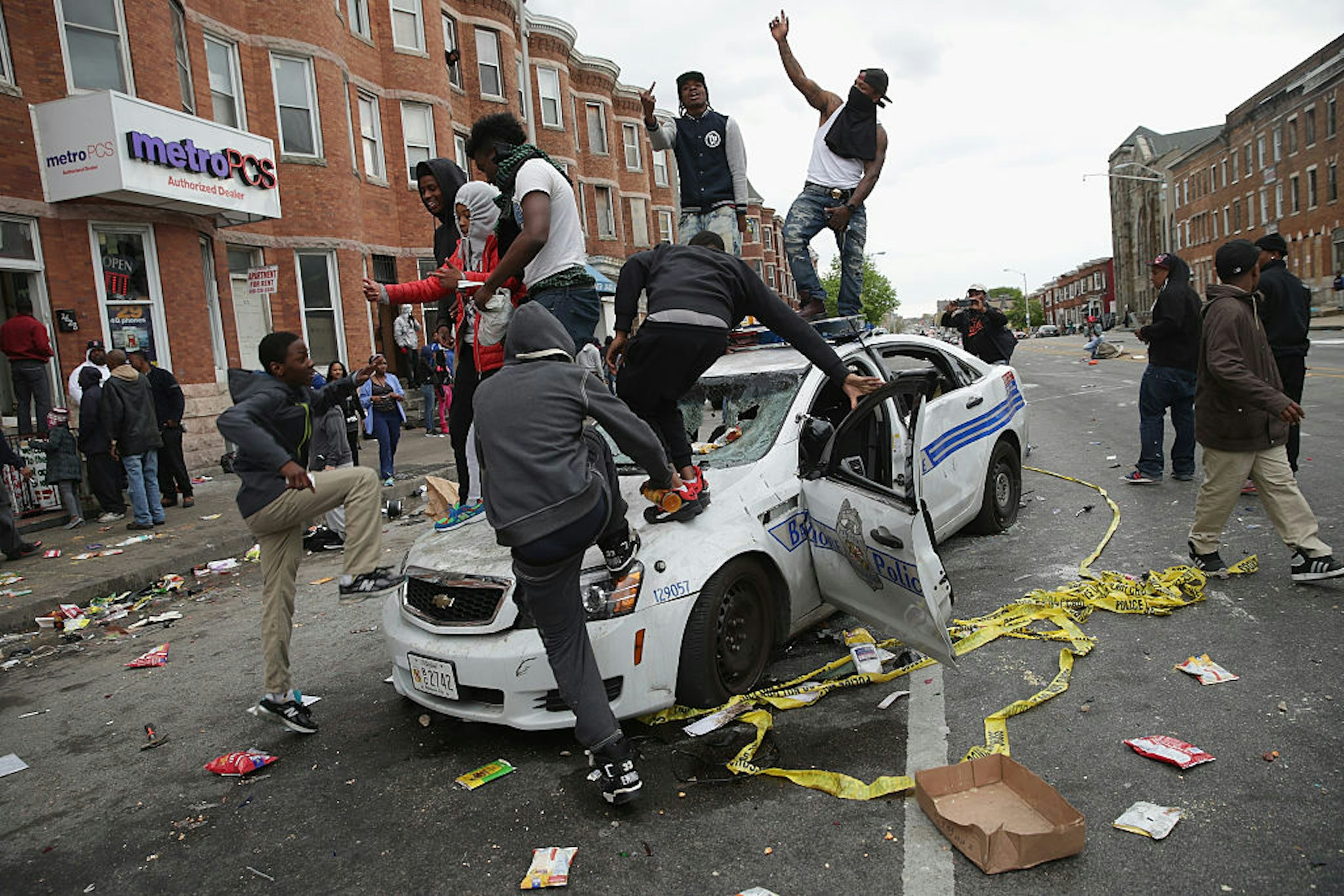 BALTIMORE, MD - APRIL 27: Demonstrators climb on a destroyed Baltimore Police car in the street near the corner of Pennsylvania and North avenues during violent protests following the funeral of Freddie Gray April 27, 2015 in Baltimore, Maryland. Gray, 25, who was arrested for possessing a switch blade knife April 12 outside the Gilmor Homes housing project on Baltimore's west side. According to his attorney, Gray died a week later in the hospital from a severe spinal cord injury he received while in police custody. (Photo by Chip Somodevilla/Getty Images)