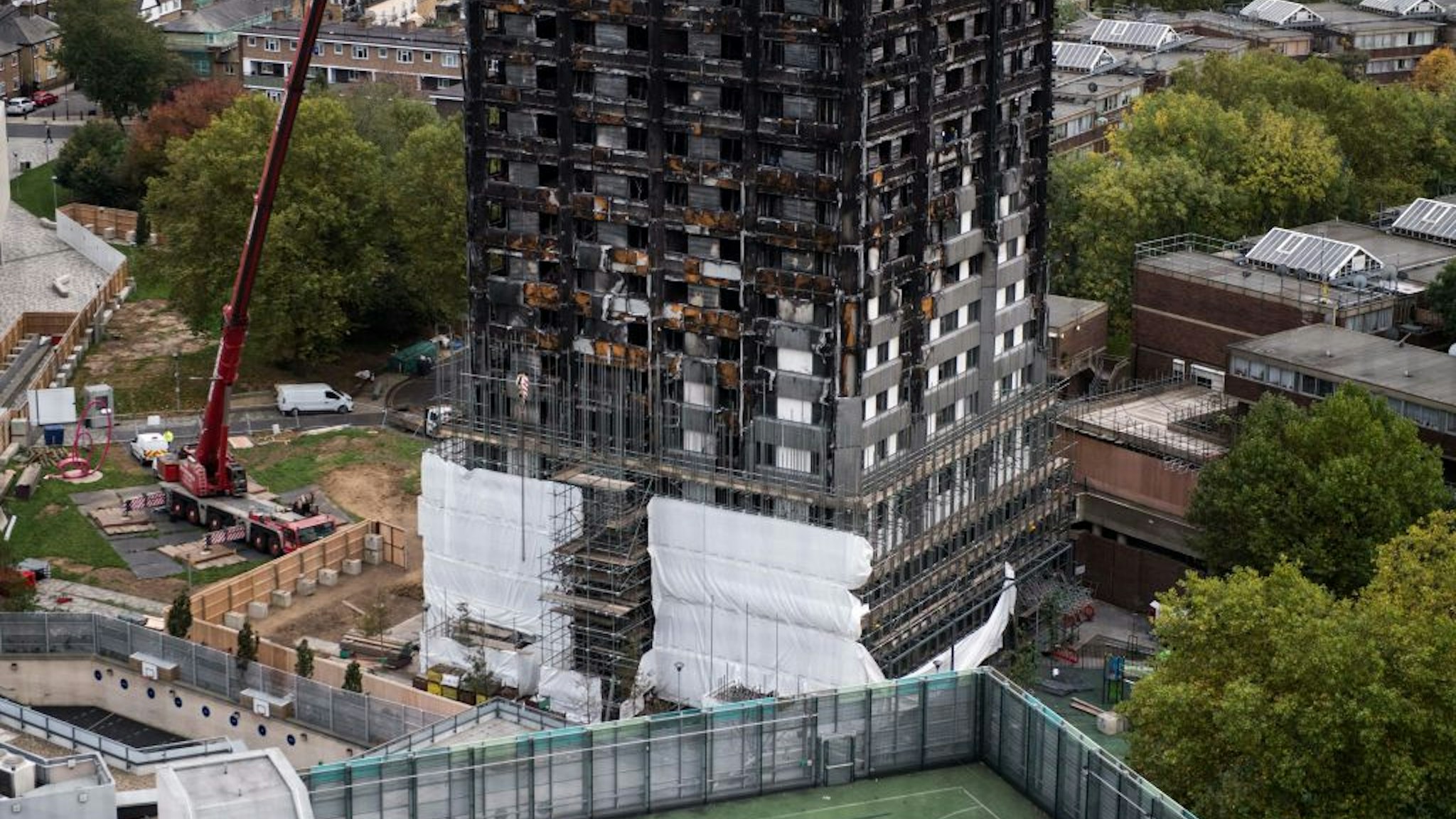 Scaffolding is seen with coverings at the base of the burned-out-shell of Grenfell Tower in London on October 17, 2017 as investigations continue into the tragedy.