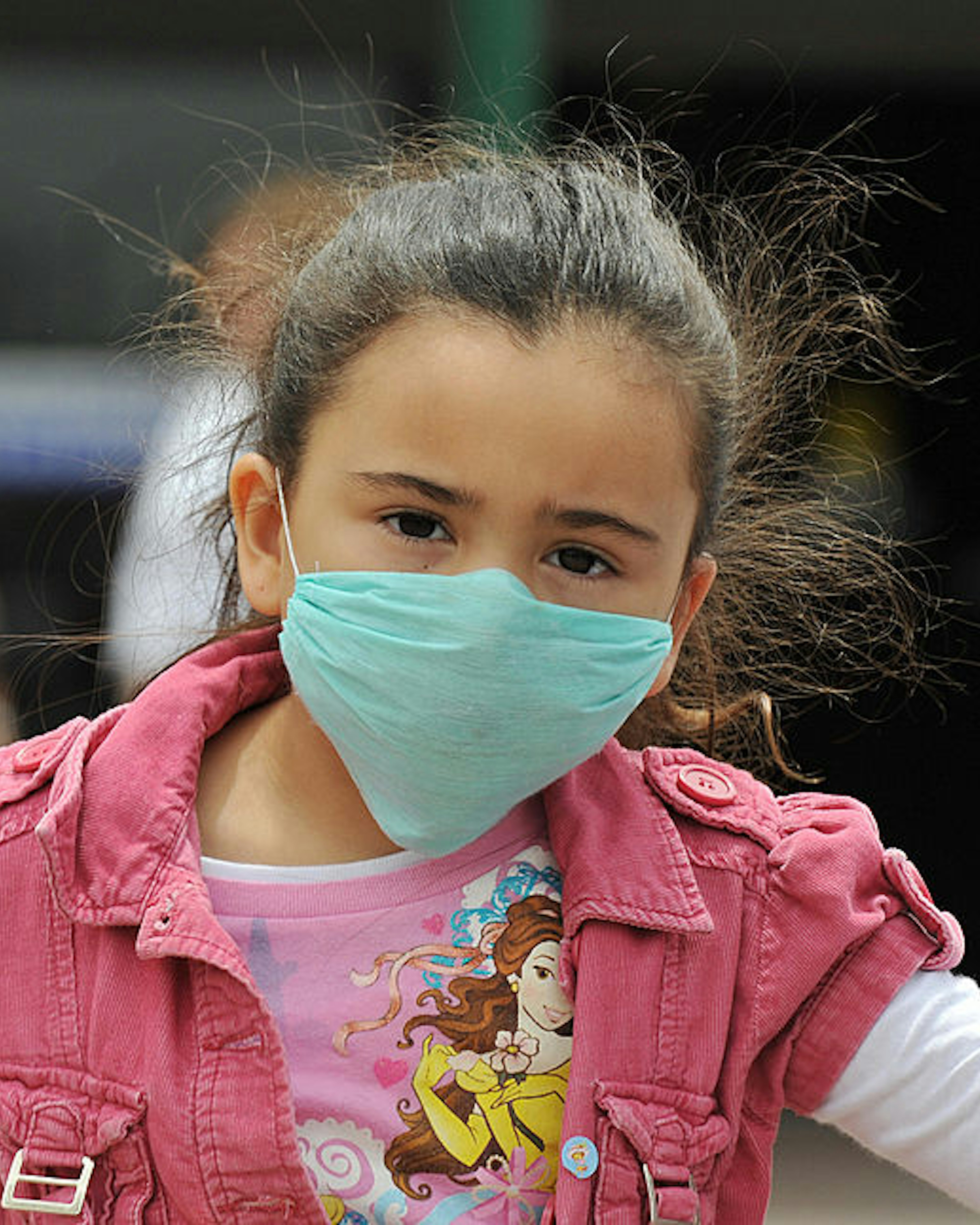 A girl, wearing a mask, holds her father's hand as they cross the international border between US and Mexico in San Ysidro, California, on April 27, 2009. The World Health Organization (WHO) raised its flu pandemic alert level from three to four, signalling a "significant increase in risk of a pandemic." The number of confirmed cases in the United States doubled to 40 on Monday, while Britain and Spain recorded their first swine flu victims. Mexico said the number of confirmed and suspected deaths from the flu had risen to 149, while some 1,600 people were thought to be infected. AFP PHOTO/Jewel SAMAD (Photo credit should read JEWEL SAMAD/AFP via Getty Images)