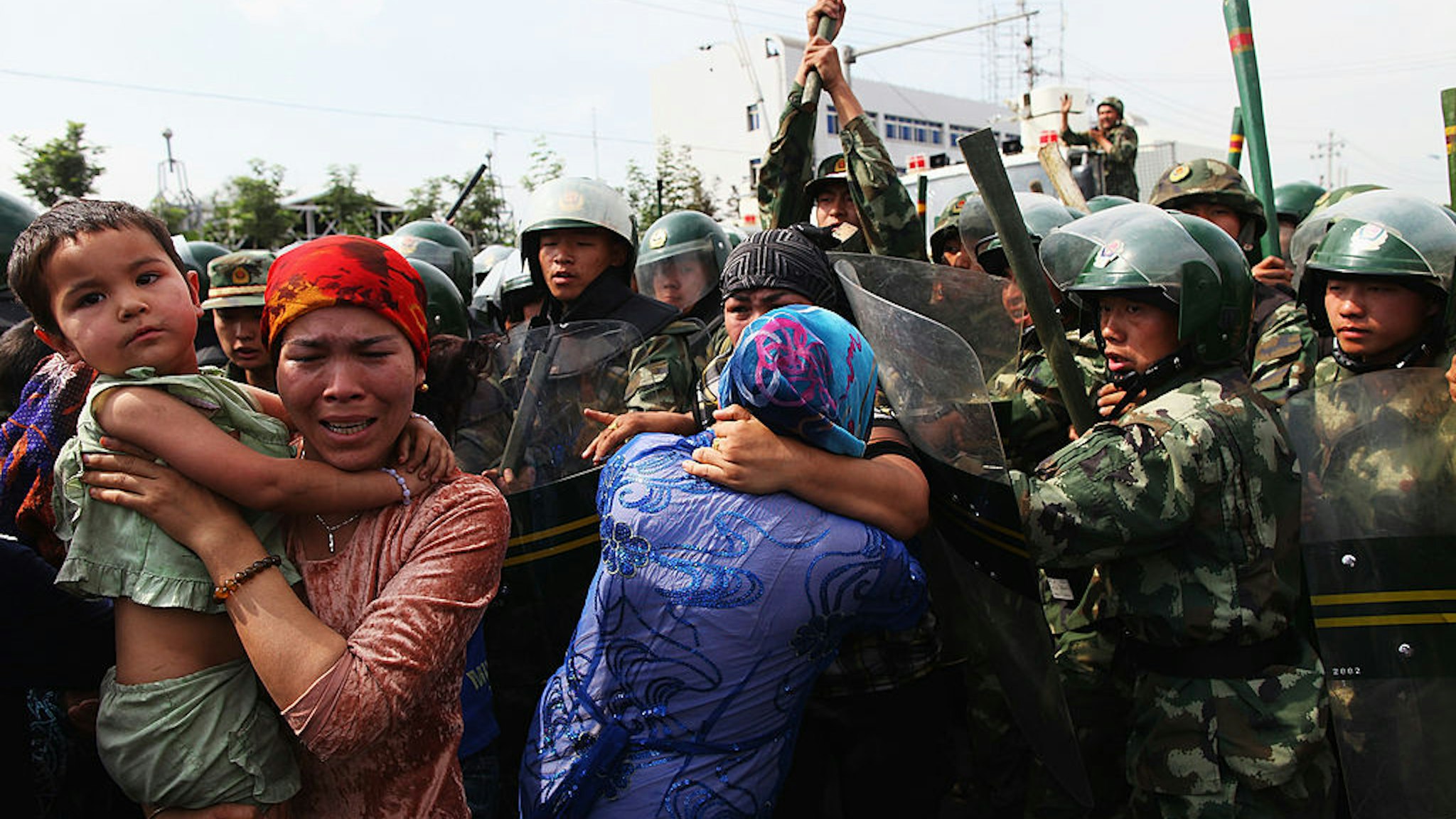 URUMQI, CHINA - JULY 07: Chinese policemen push Uighur women who are protesting at a street on July 7, 2009 in Urumqi, the capital of Xinjiang Uighur autonomous region, China. Hundreds of Uighur people have taken to the streets protesting after their relatives were detained by authorities after Sunday's protest. Ethnic riots in the capital of the Muslim Xinjiang region on Sunday saw 156 people killed. Police officers, soldiers and firefighters were dispatched to contain the rioting with hundreds of people being detained. (Photo by Guang Niu/Getty Images)