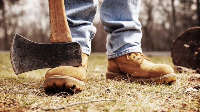 Low section of lumberjack with pick axe on field - stock photo