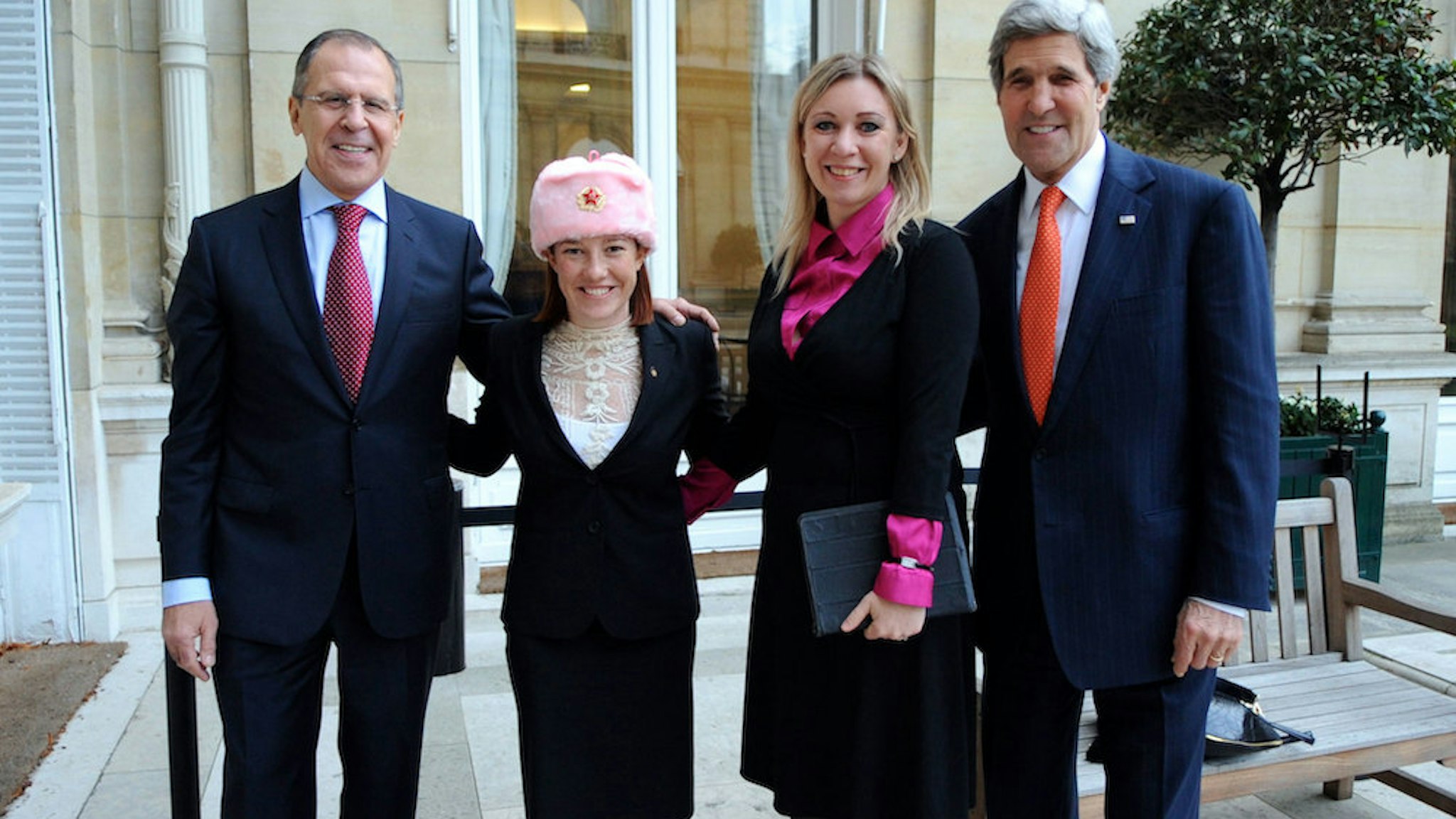U.S. Department of State Spokesperson Jennifer Psaki -- sporting a shapka, or fur hat with ear flaps, given to her by Russian counterpart Maria Zakharova -- stands with Zakharova between U.S. Secretary of State John Kerry and Russian Foreign Minister Sergey Lavrov in Paris, France, on January 13, 2014. (State Department photo/Public Domain)