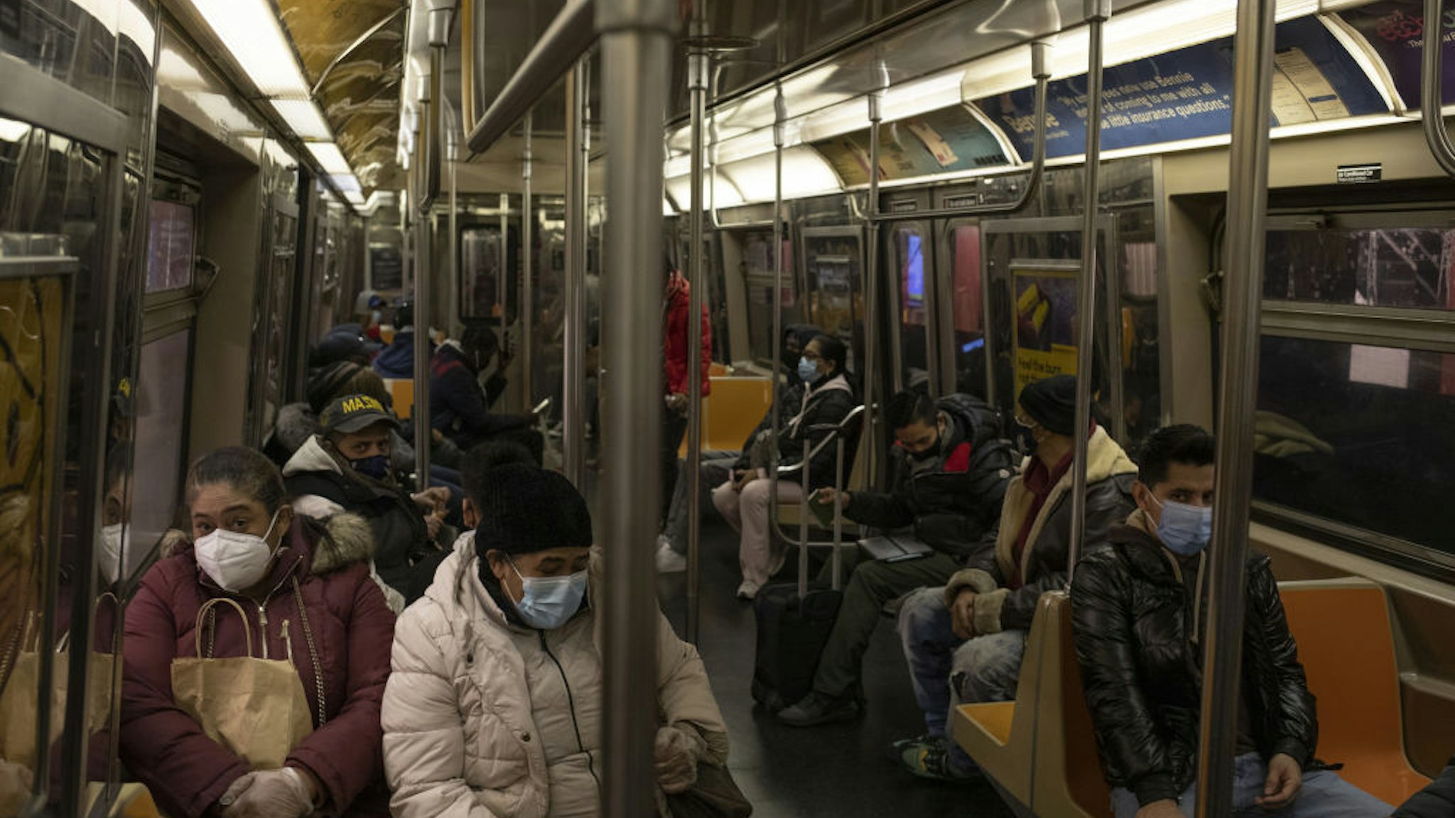 Commuters wearing protective masks travel in a subway train in New York, U.S., on Thursday, Dec. 10, 2020. New York City had its credit rating cut by Fitch Ratings because of the impact the coronavirus pandemic is having on the city's economy.