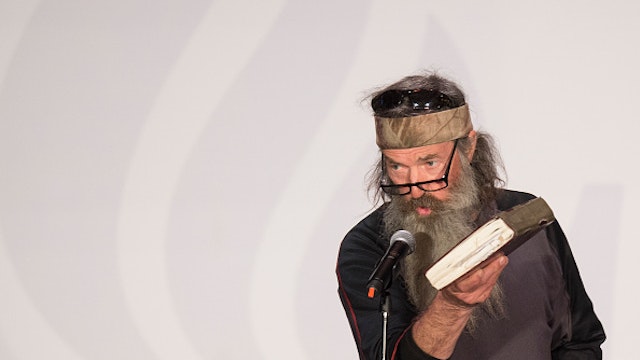 Reality TV's Duck Dynasty star Phil Robertson holds up his Bible during a campaign rally for Republican presidential candidate Ted Cruz in Charleston, South Carolina, February 19, 2016. / AFP / JIM WATSON