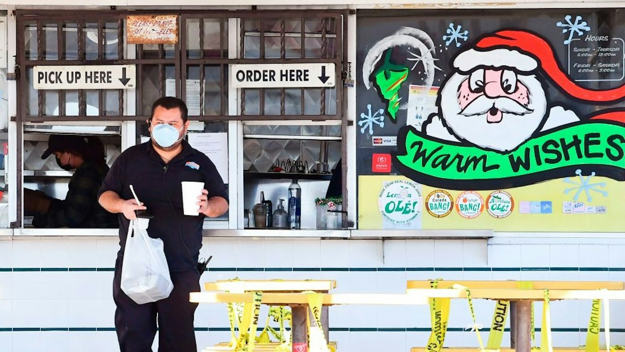 A customer receives his takeout order from a restaurant in Los Angeles, California on December 1, 2020. - A county-wide coronavirus regulations went into effect again on November 30 for three weeks amid ever increasing numbers of positive Covid-19 cases and fears of overwhelmed hospitals. Aid for restaurants will begin on December 3, with the start of the Keep Los Angeles County Dining Grant Program , allowing eligible restaurants which have lost business due to countywide coronavirus health regulations to apply for and receive up to $30,000 in aid. (Photo by Frederic J. BROWN / AFP) (Photo by FREDERIC J. BROWN/AFP via Getty Images)