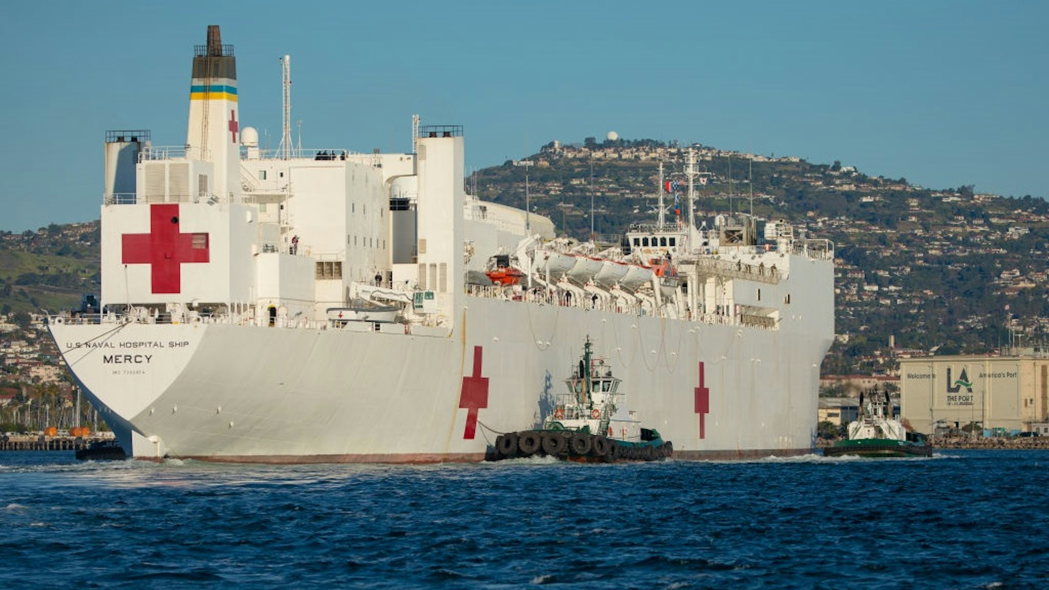 Tugboats guide the USNS Mercy hospital ship to moor at the Port of Los Angeles in Los Angeles, California, U.S., on Friday, March 27, 2020.